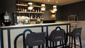 Una zona de bar con mostrador, estanterías llenas de botellas y dos taburetes de bar.
