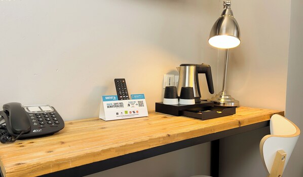 A hotel desk with a telephone, a coffee maker, a lamp, and a card offering free breakfast. - Hotel Le Faisan Dore (Écouché-les-Vallées)