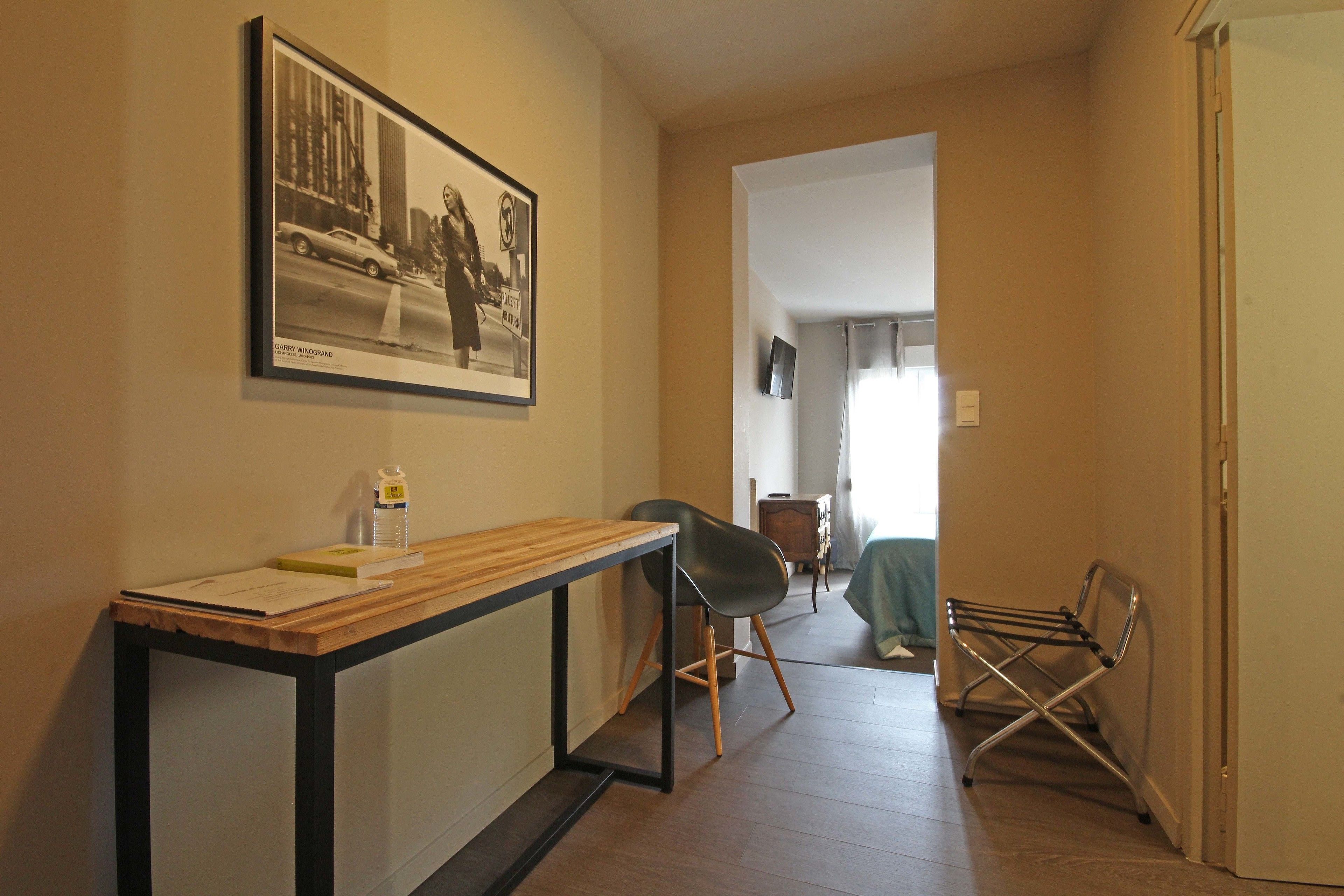 A hallway with a wooden table, a black chair, and a drying rack.