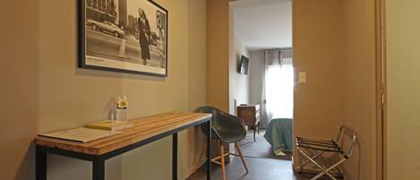 A hallway with a wooden table, a black chair, and a drying rack.