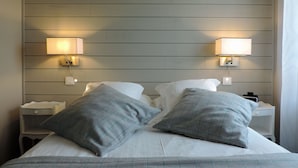 Una habitación de hotel con una cama, dos mesitas de noche y lámparas fijadas a la pared.