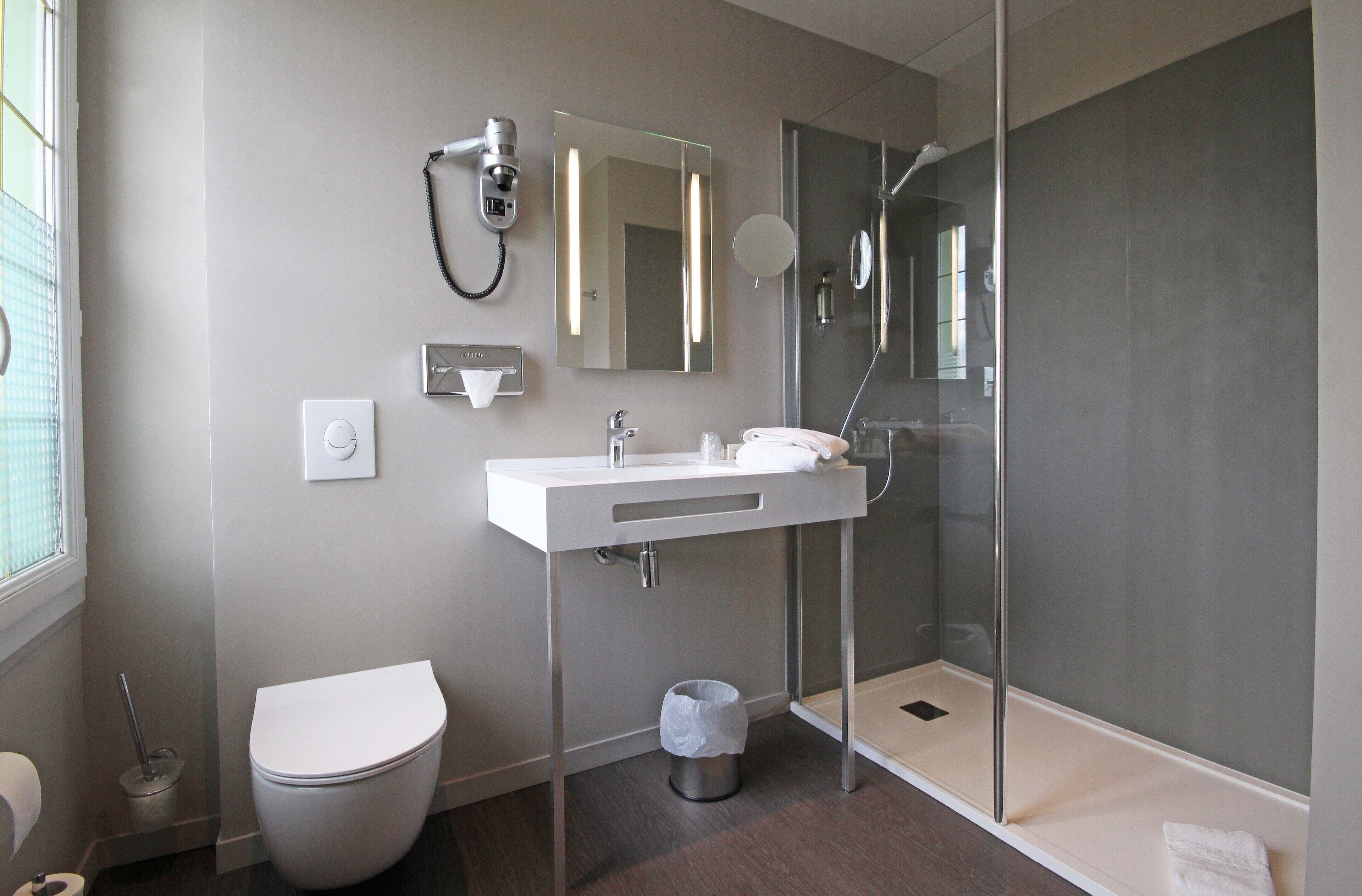 Een moderne badkamer met toilet, wastafel en douche.