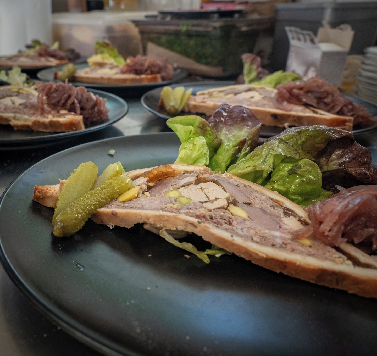 Una mesa de comedor con platos de comida, incluyendo carne en rodajas y encurtidos.