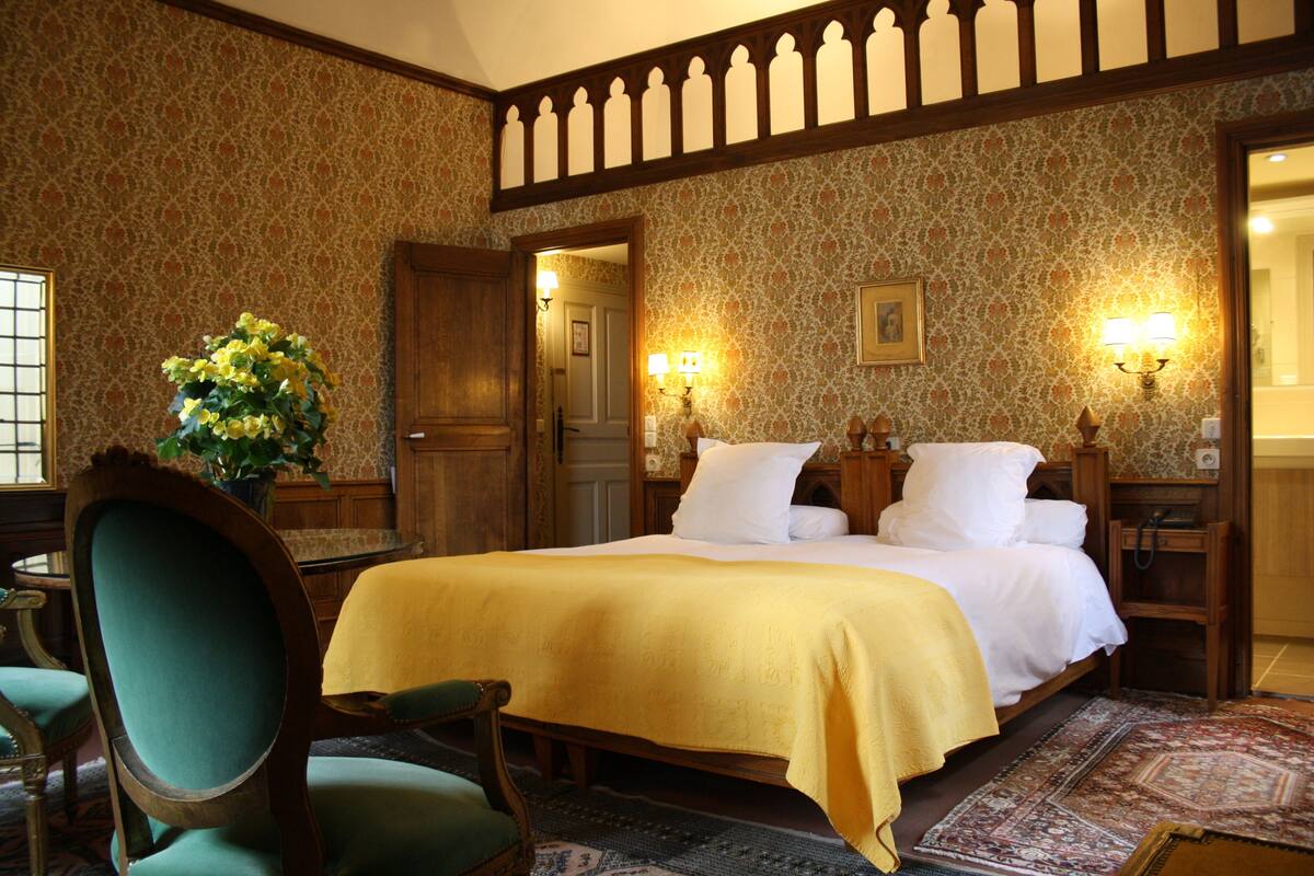 A traditional room with a large bed, wooden furniture, and patterned wallpaper.