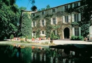 Um edifício histórico com um amplo pátio, um lago refletor e áreas de estar ao ar livre.