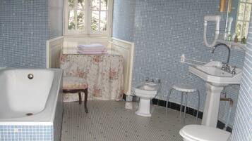 A bathroom with a bathtub, a sink, a toilet, and a window.