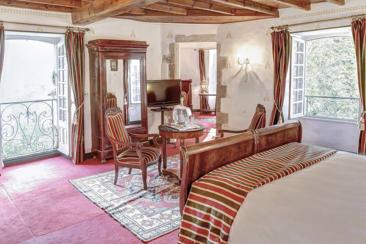 A room with a bed, a TV, a wooden cabinet, a table, and chairs.