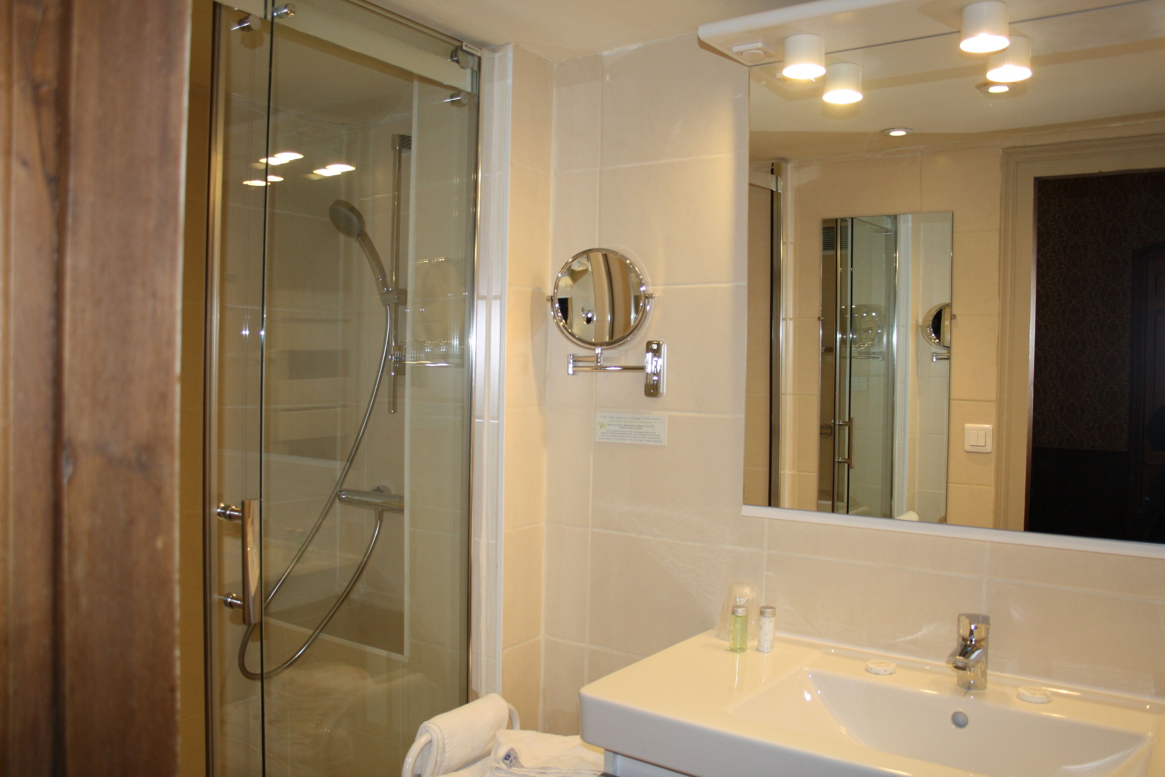 Un baño moderno con cabina de ducha de vidrio, un lavamanos blanco y un espejo grande.