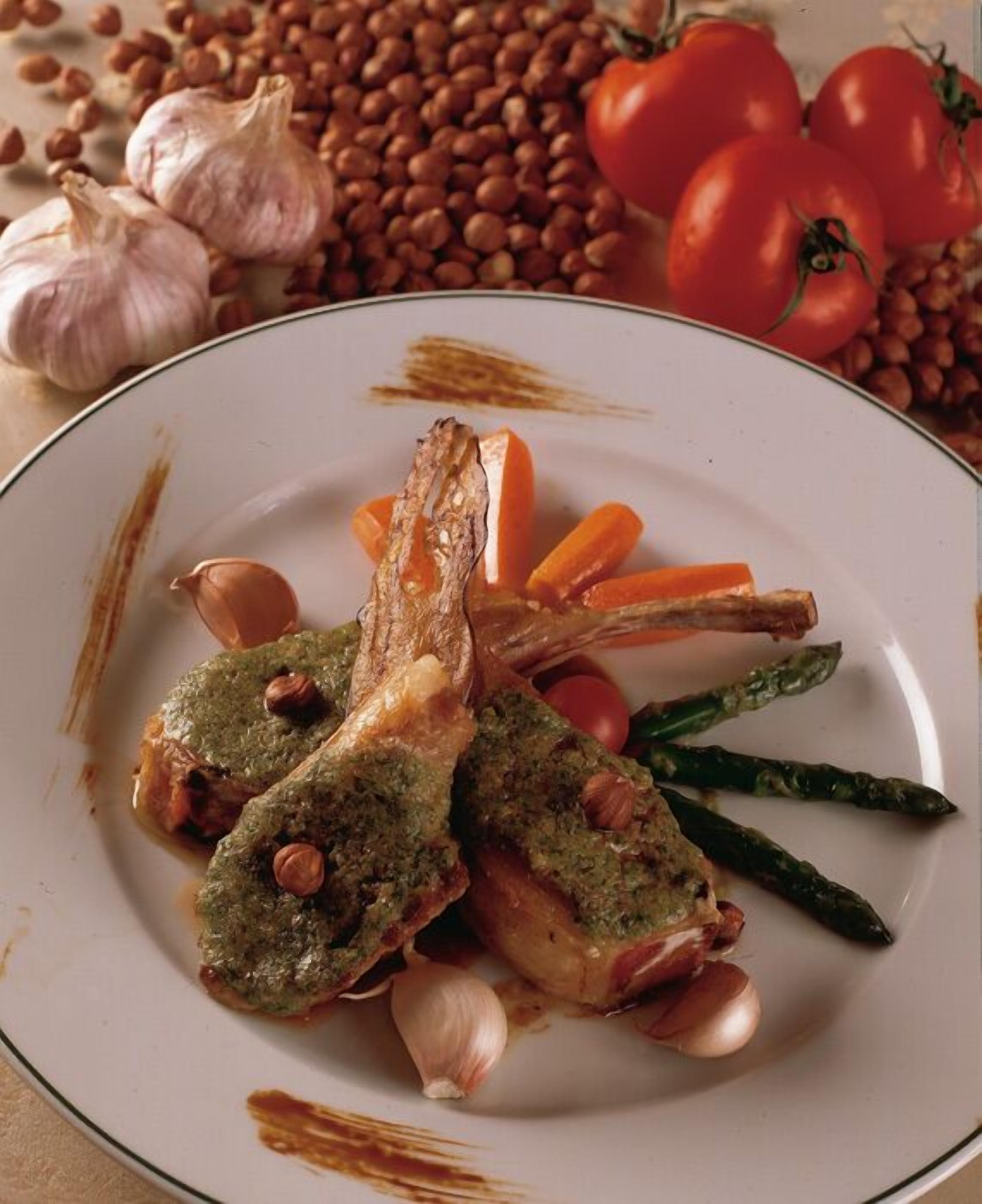 Un piatto con costolette di agnello alla griglia, asparagi e carote.