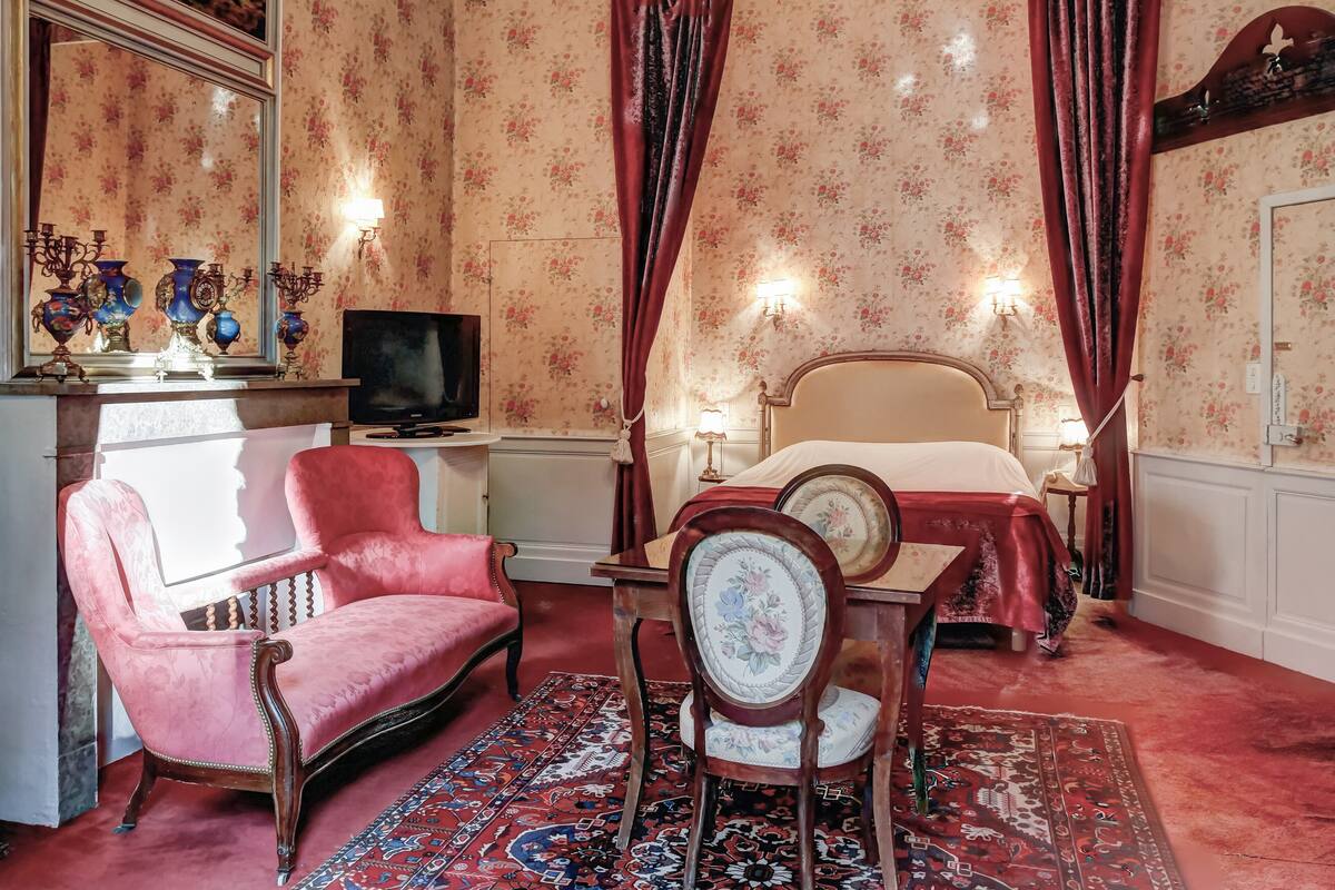 A room with a bed, a desk with a television, a chair, and a rug.