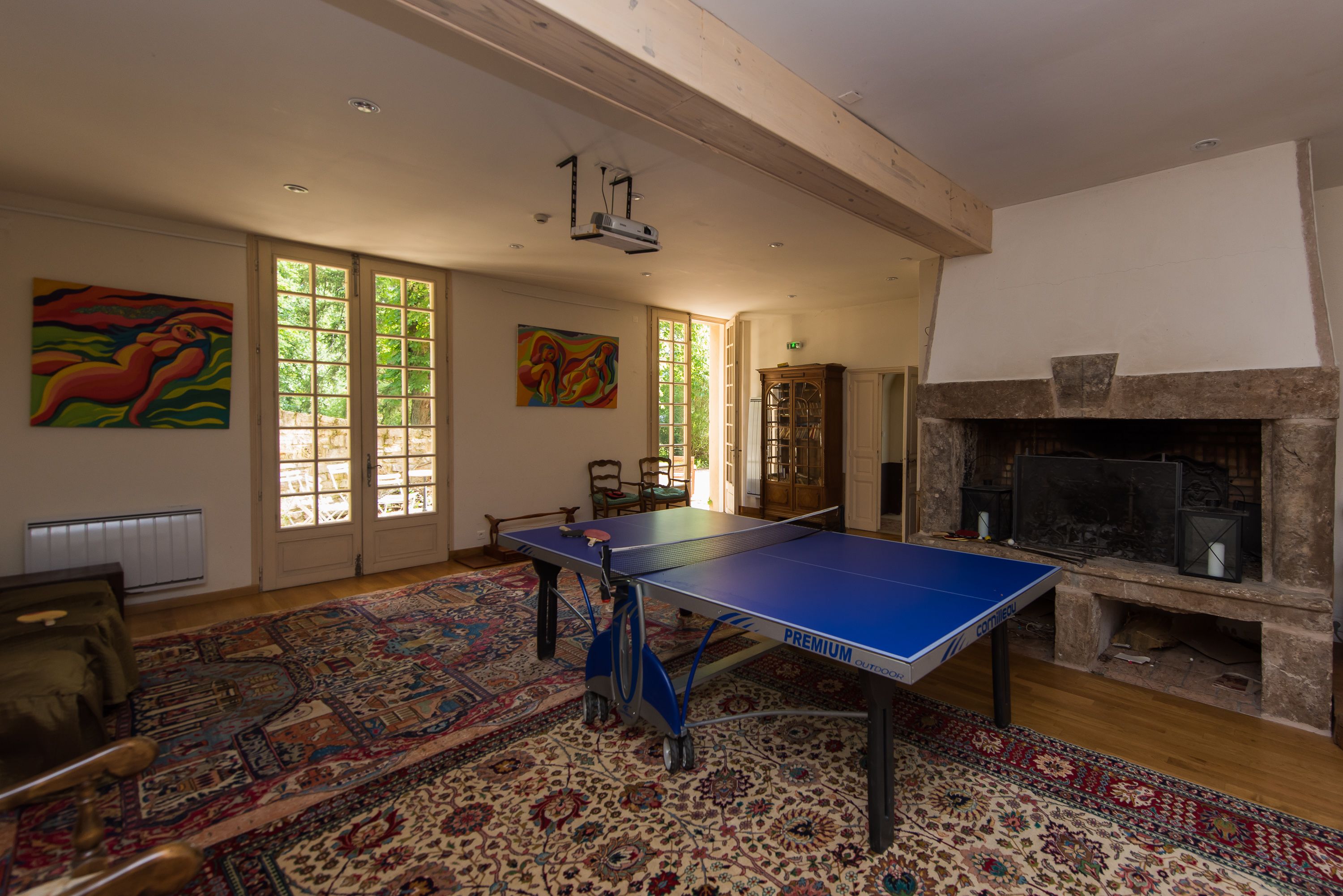 A spacious room with a ping pong table, a fireplace, and large windows.
