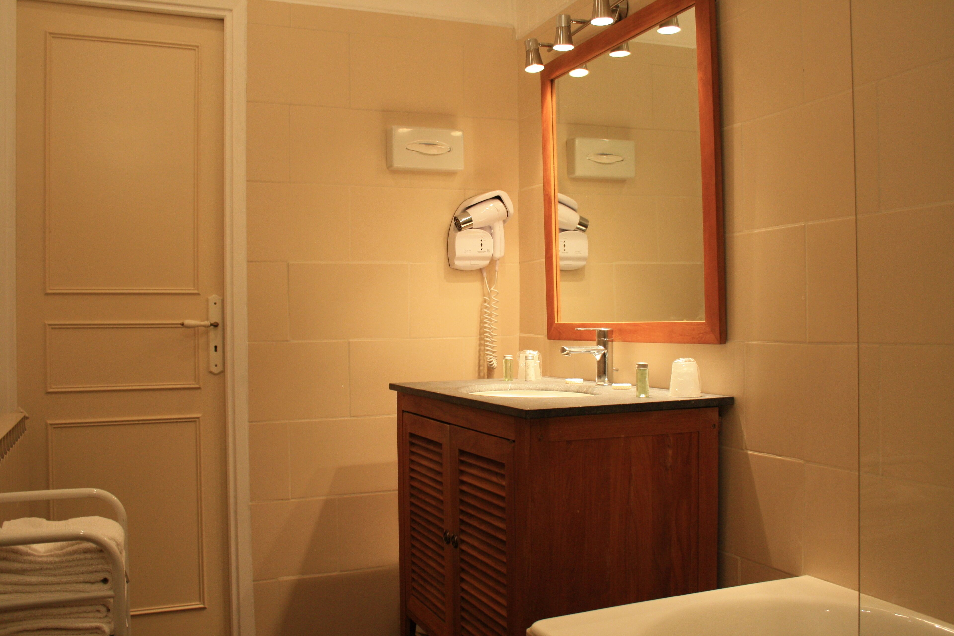 A bathroom with a wooden vanity, a sink, a hairdryer, and a mirror.