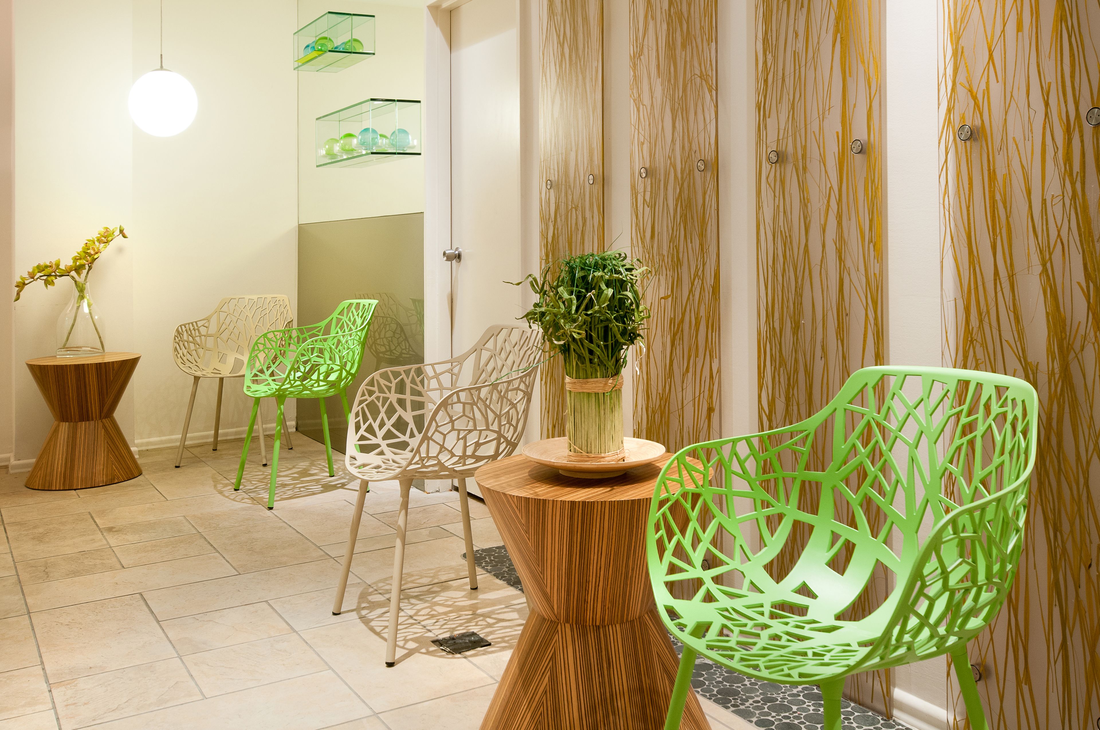 A modern interior with green chairs, a wooden table, and a vase with flowers.