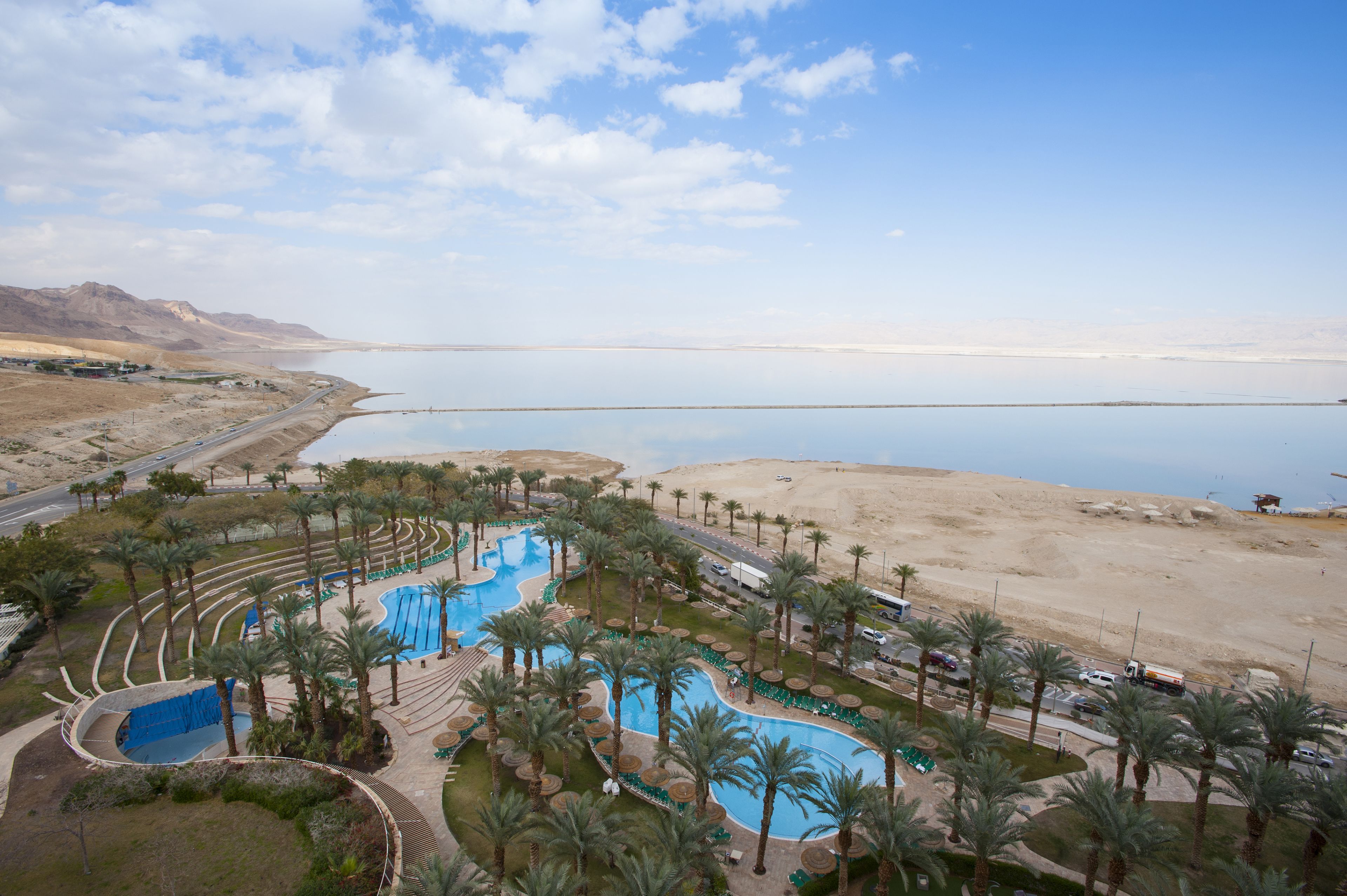 A resort with a large swimming pool, palm trees, and a desert landscape.