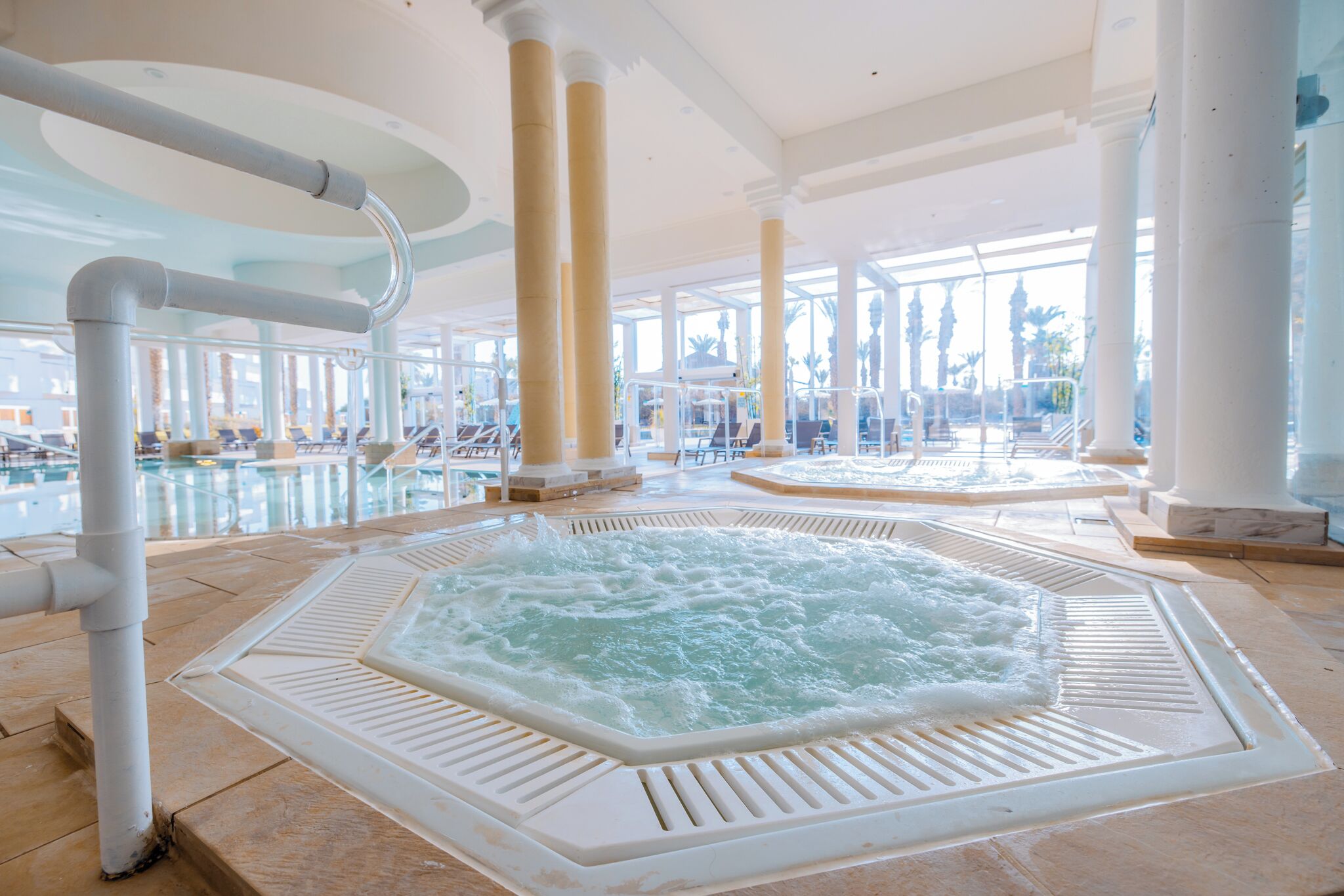 A large indoor hot tub area with clear views of the pool and outdoor scenery.