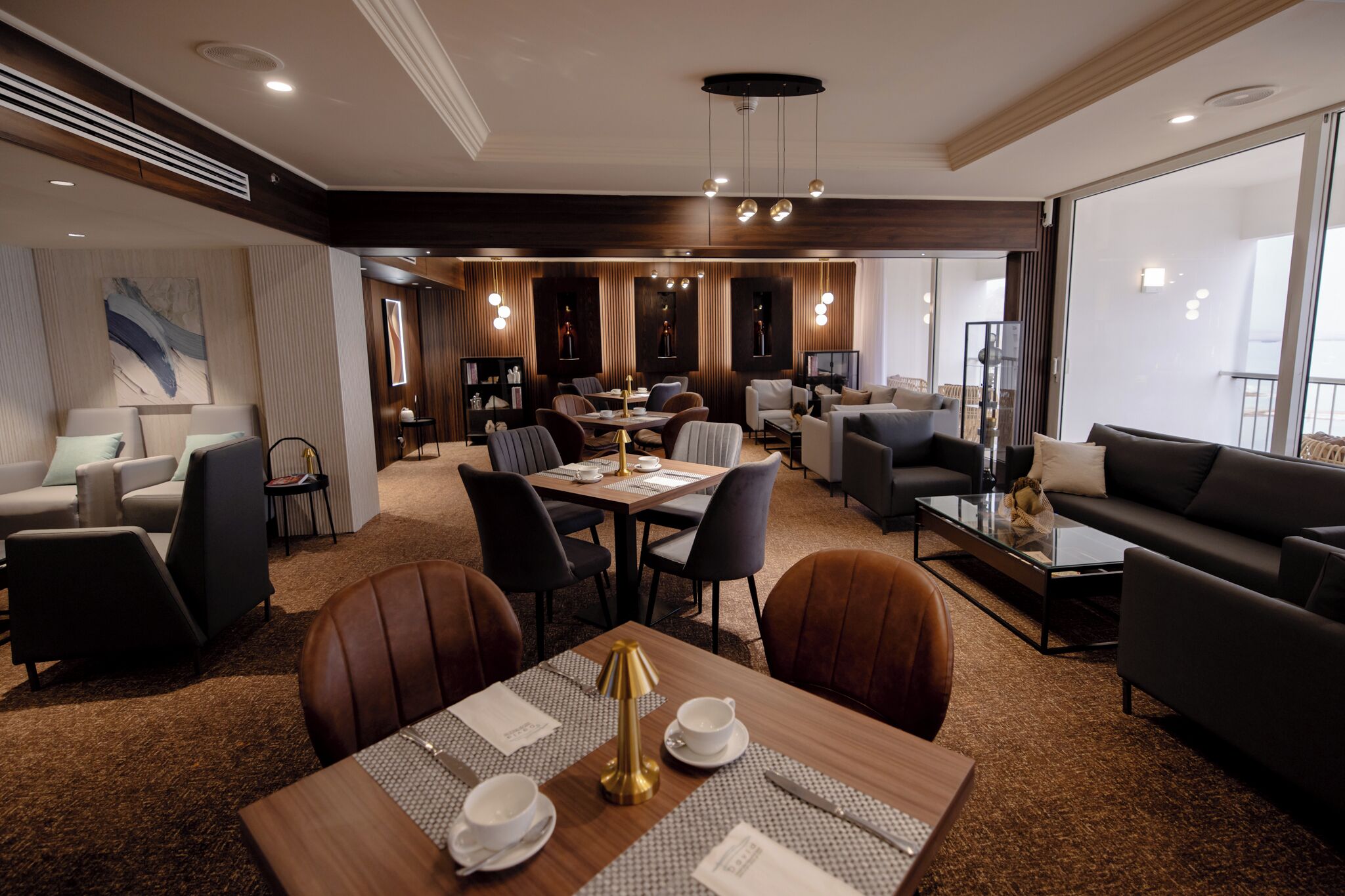 Een moderne hotellobby met een eetgedeelte, zitplaatsen en uitzicht op het balkon.