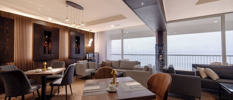 A modern interior with a dining area, sofas, and a large window offering a view.