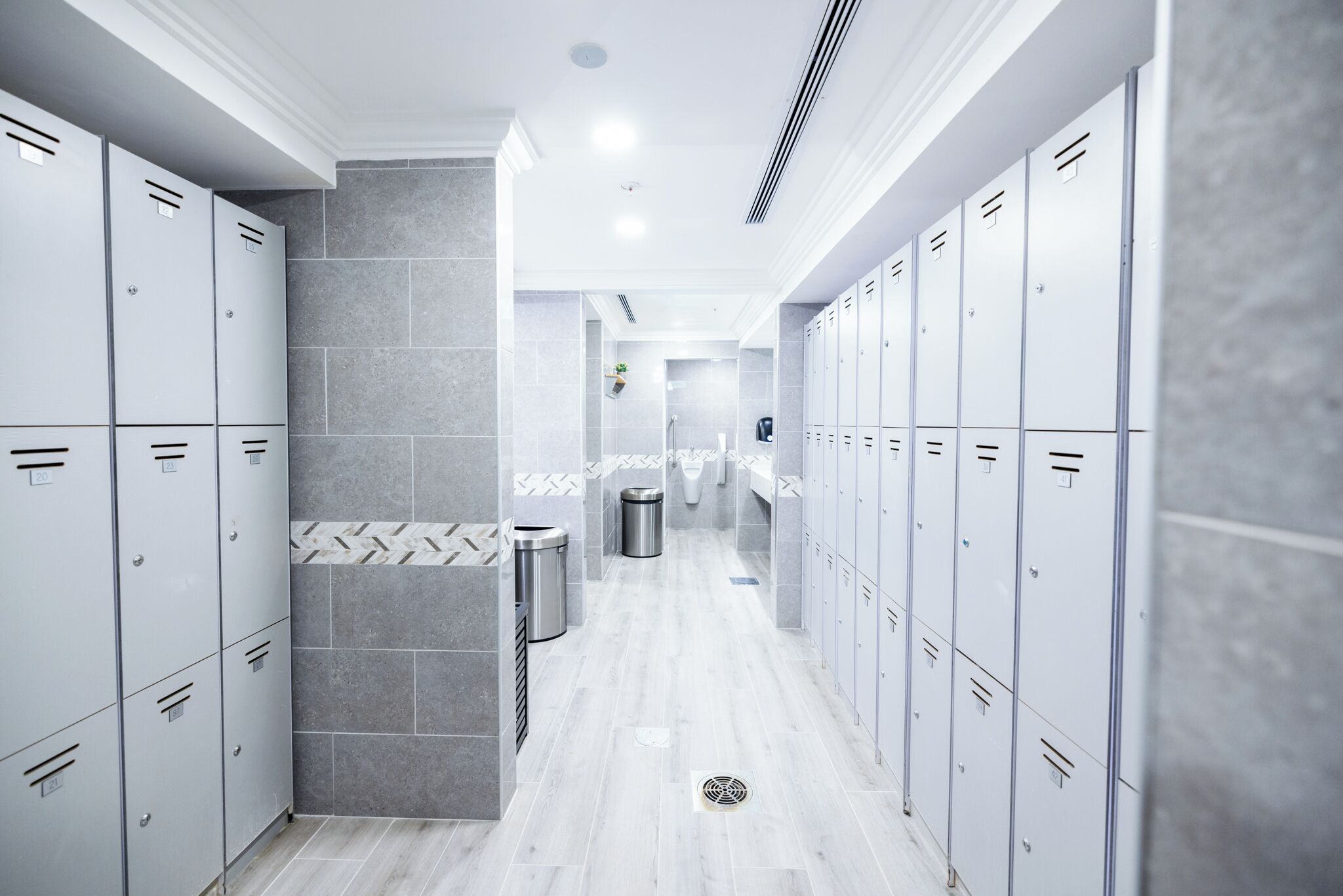 A clean, modern locker room with grey lockers and a tiled floor.