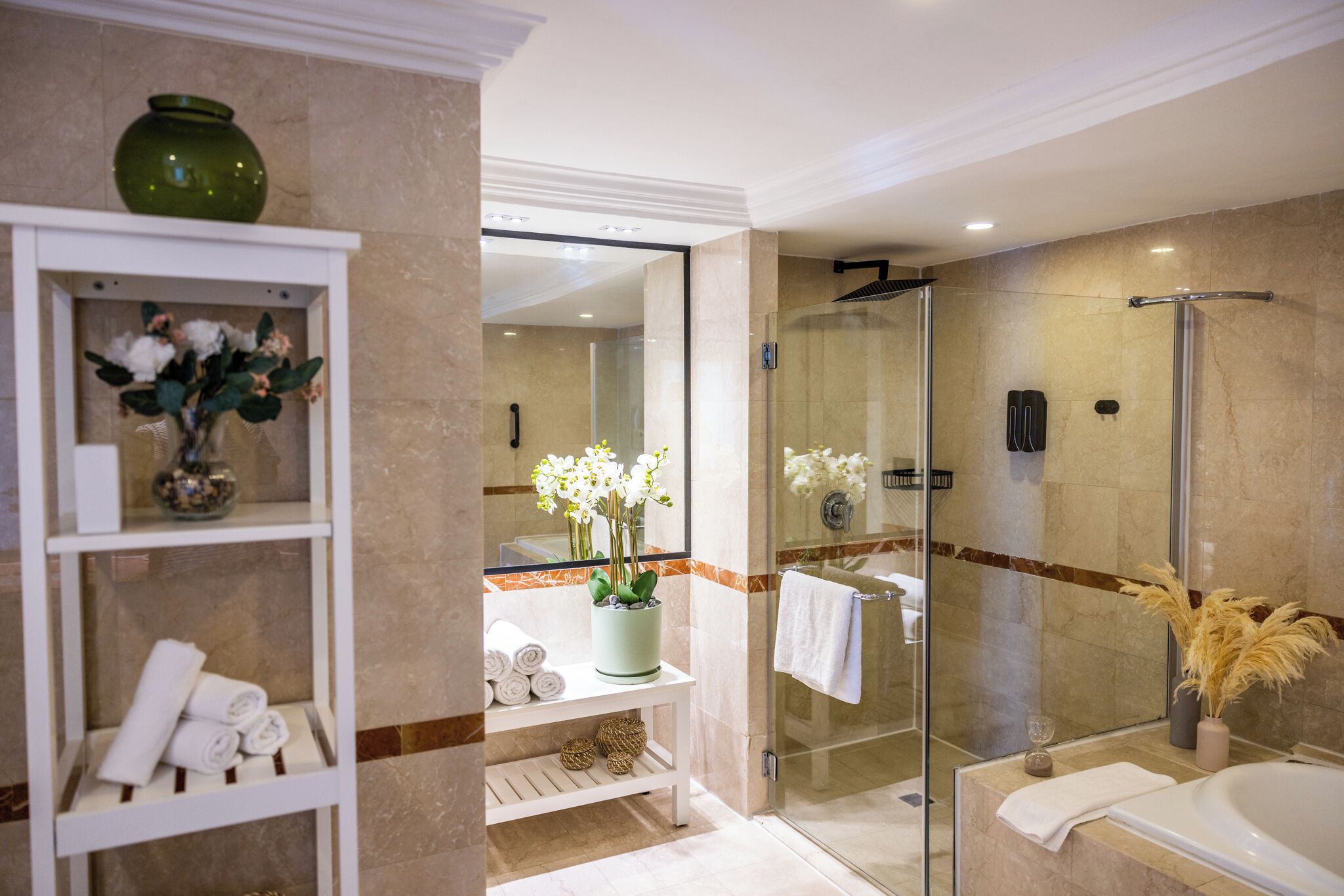A modern bathroom with a glass shower enclosure, a white bathtub, and a vanity with a mirror.