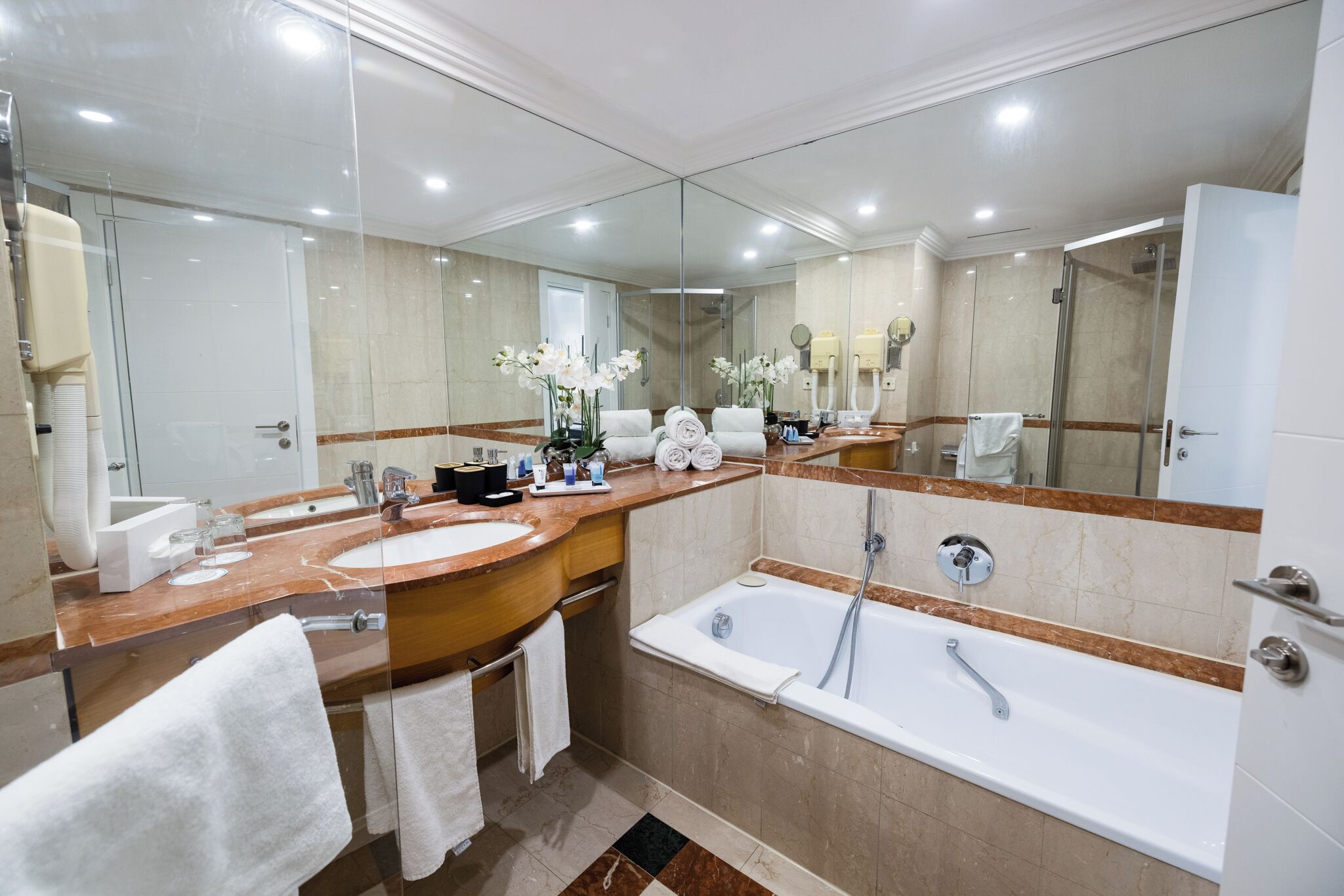 Une salle de bain moderne avec un grand miroir, deux lavabos, une baignoire et une douche.