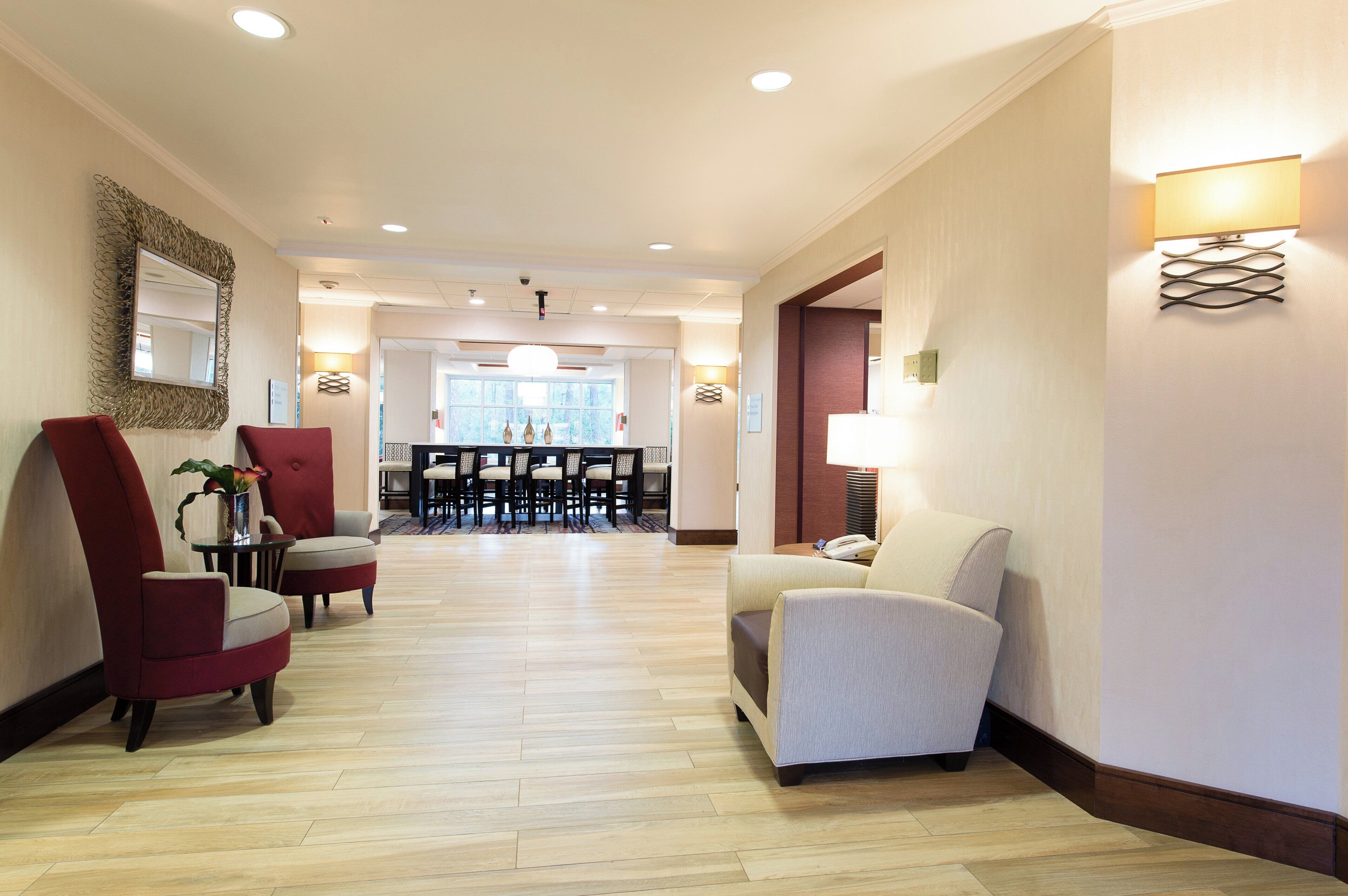 A hotel lobby with a reception desk, seating area, and a dining space.