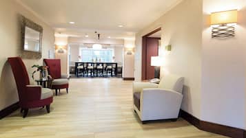 A hotel lobby with a reception desk, seating area, and a dining space.