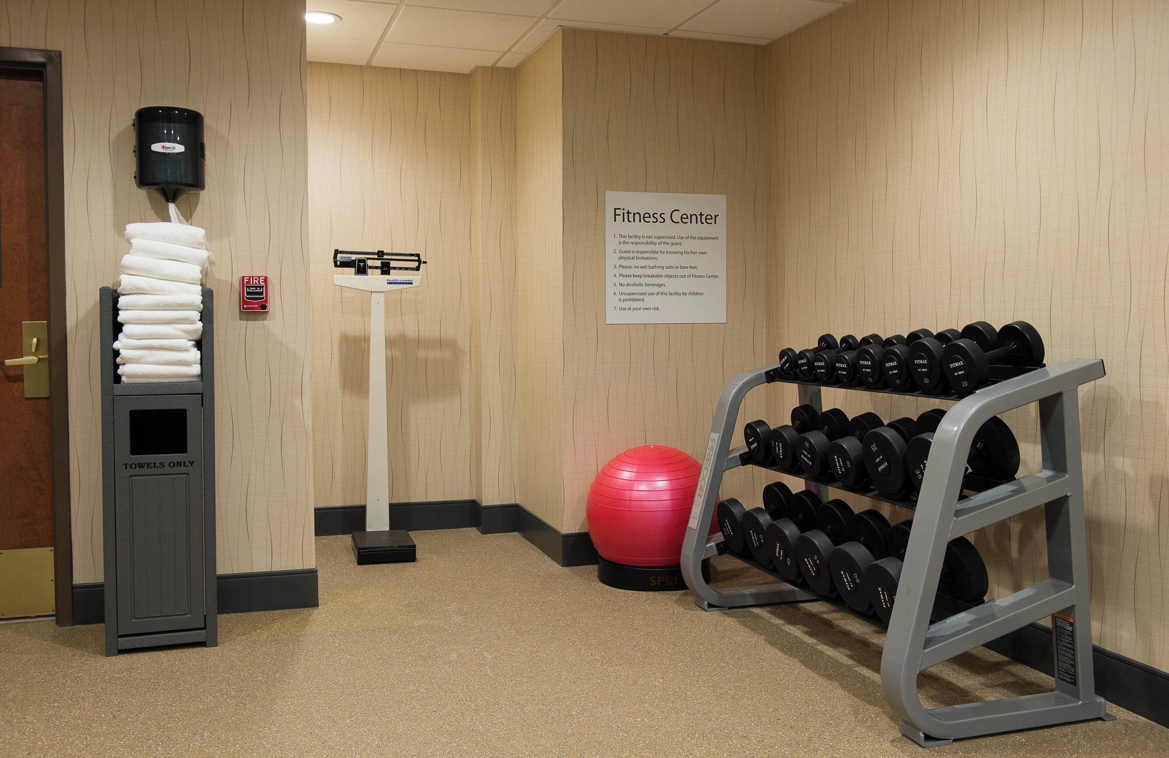 Un gimnasio con un banco de mancuernas, una pelota de ejercicios roja y un medidor de salud.