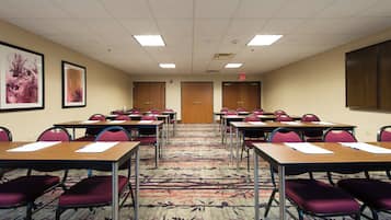 A conference room with multiple tables and chairs, a patterned carpet, and framed artwork on the walls.