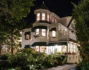 A large, two-story house with a prominent turret and multiple windows, surrounded by lush greenery. - Harbour Towne Inn on the Waterfront (Boothbay Harbor)