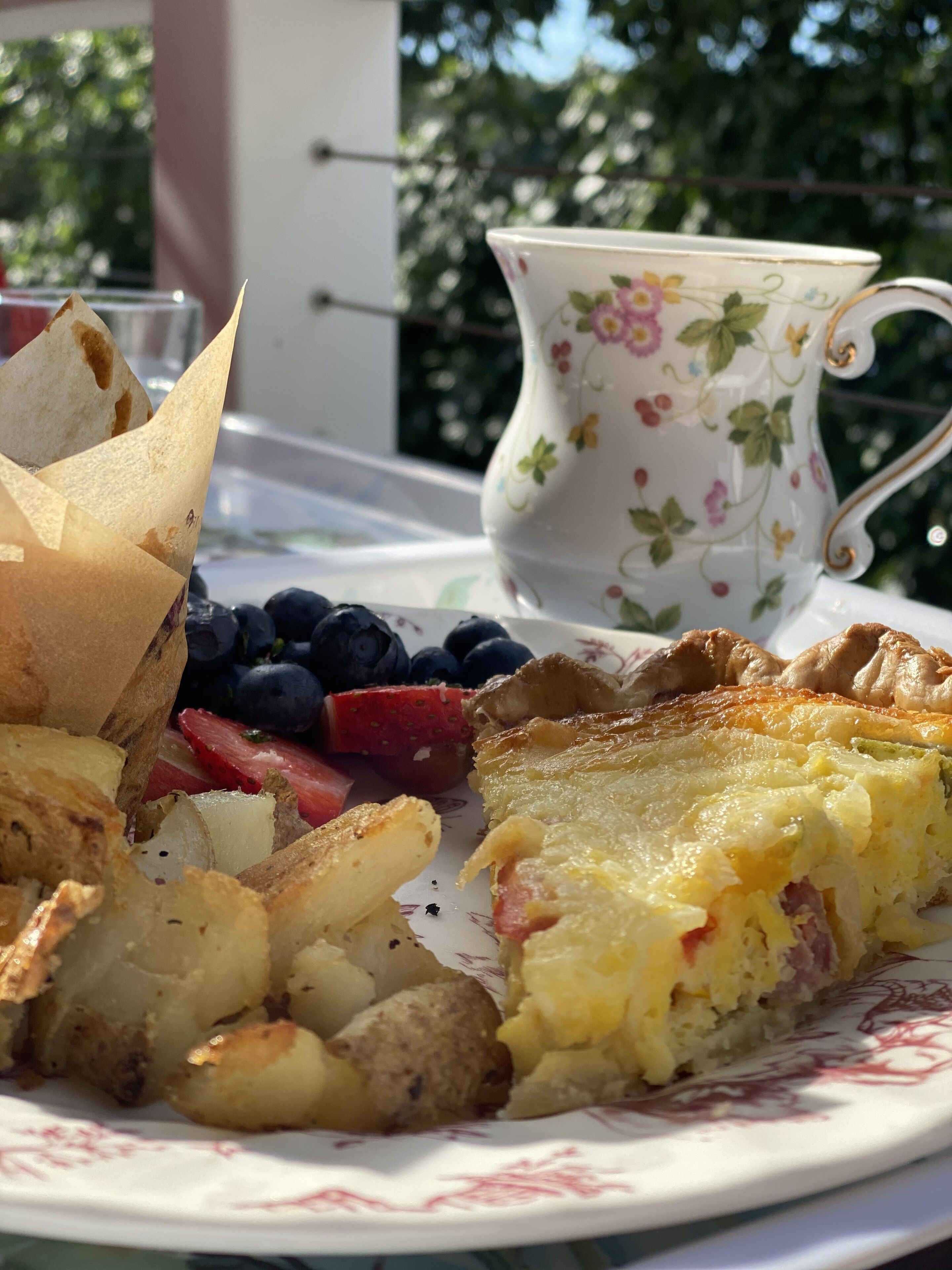 A plate of food with toast, potatoes, a slice of quiche, blueberries, and strawberries.