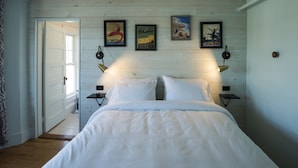 A bedroom with a bed, two bedside tables, and wall-mounted lamps. - Higgins Beach Inn (Scarborough)