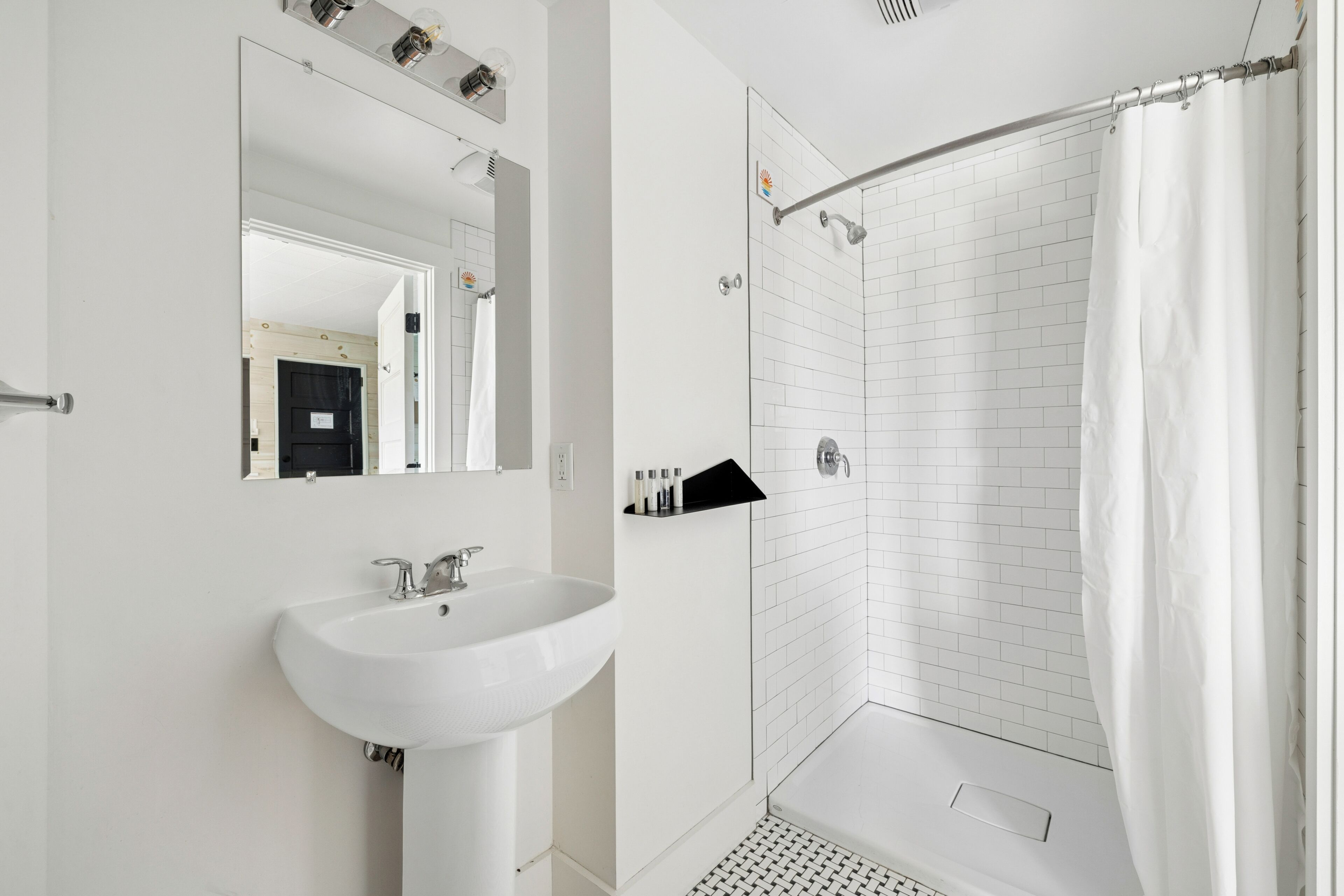 Een moderne badkamer met een witte wastafel, een spiegel en een douchehoek.