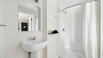 Een moderne badkamer met een witte wastafel, een spiegel en een douchehoek.