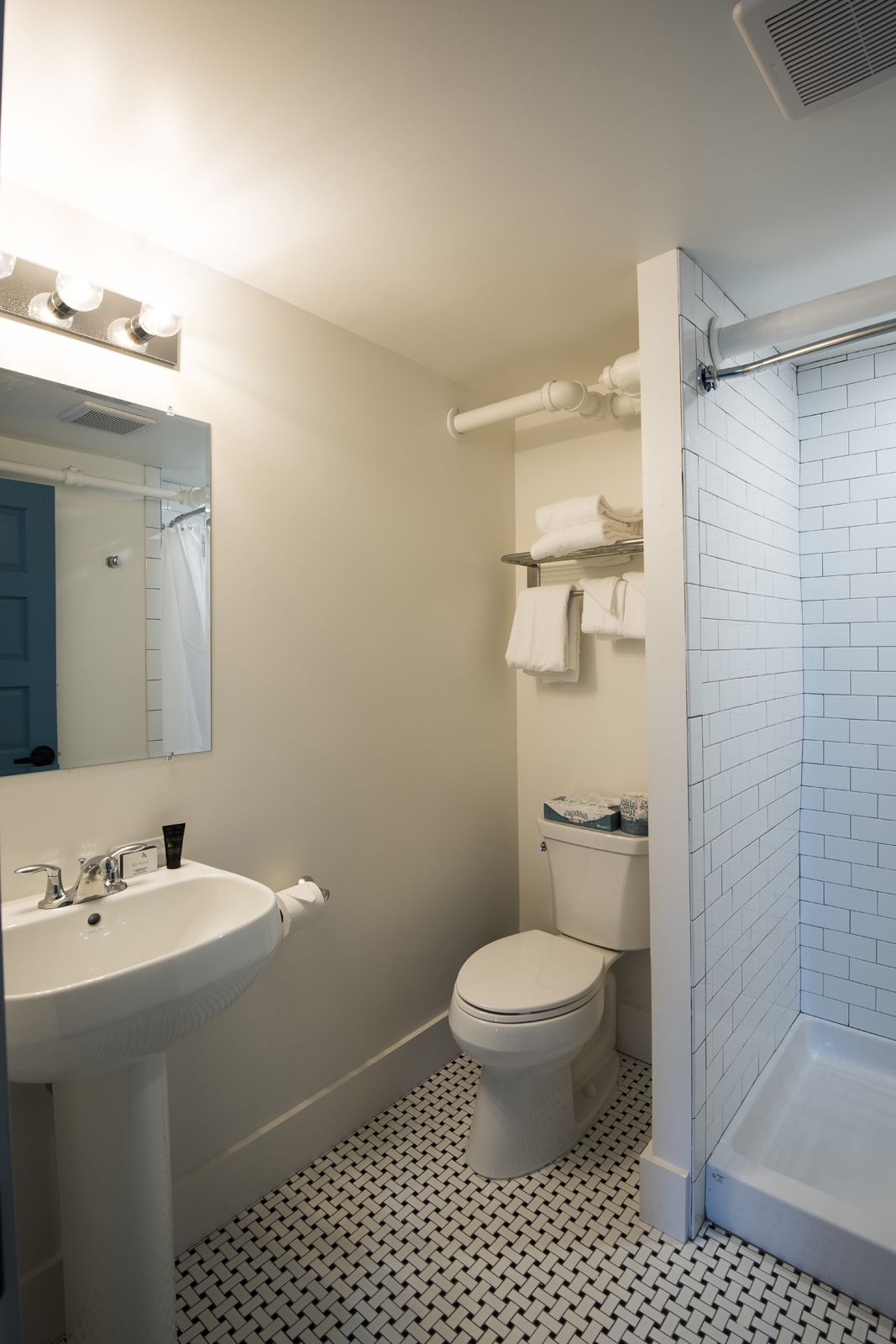 A bathroom with a white sink, toilet, and a shower area with tiled walls.