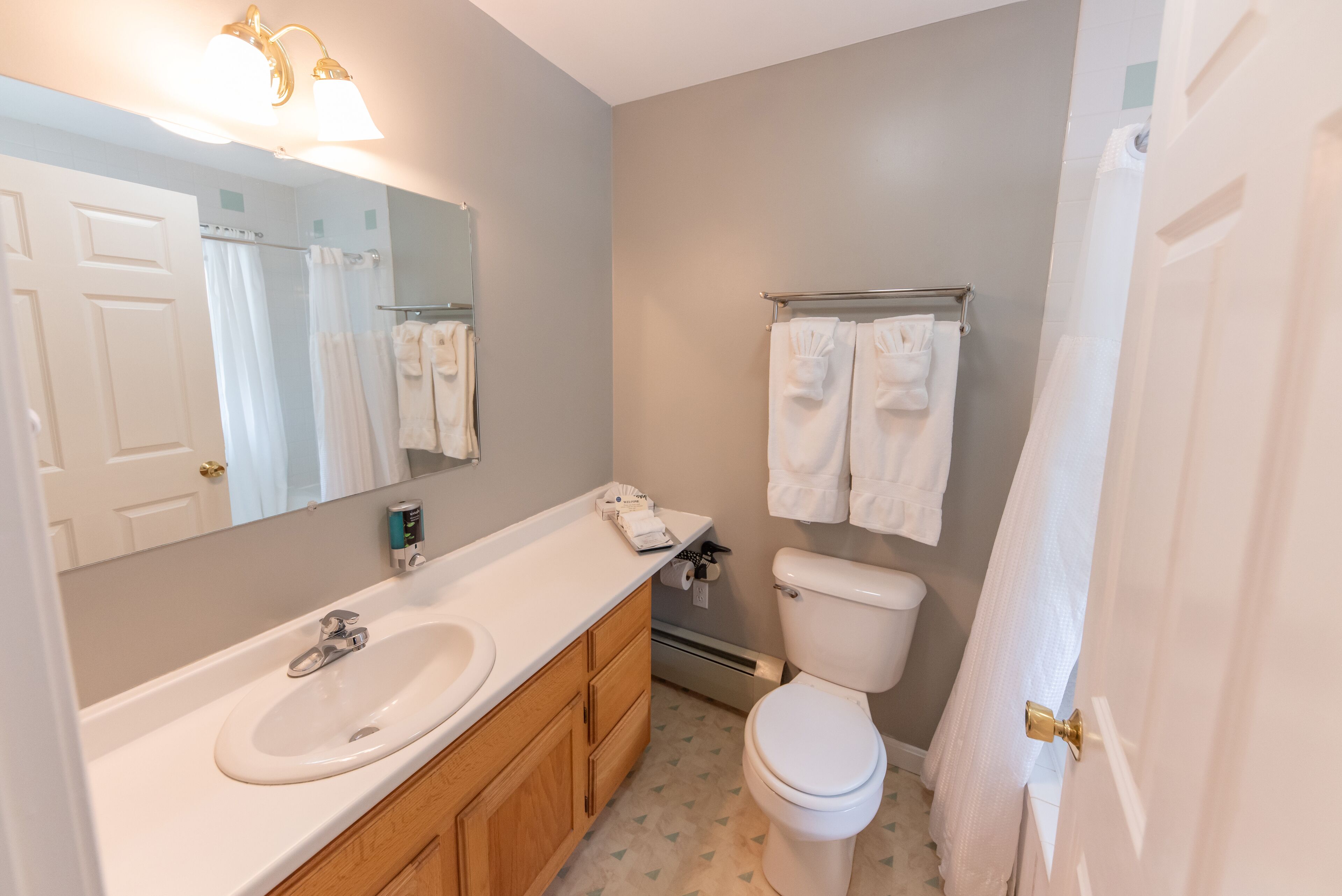 A bathroom with a white sink, wooden cabinets, a toilet, and a towel rack.