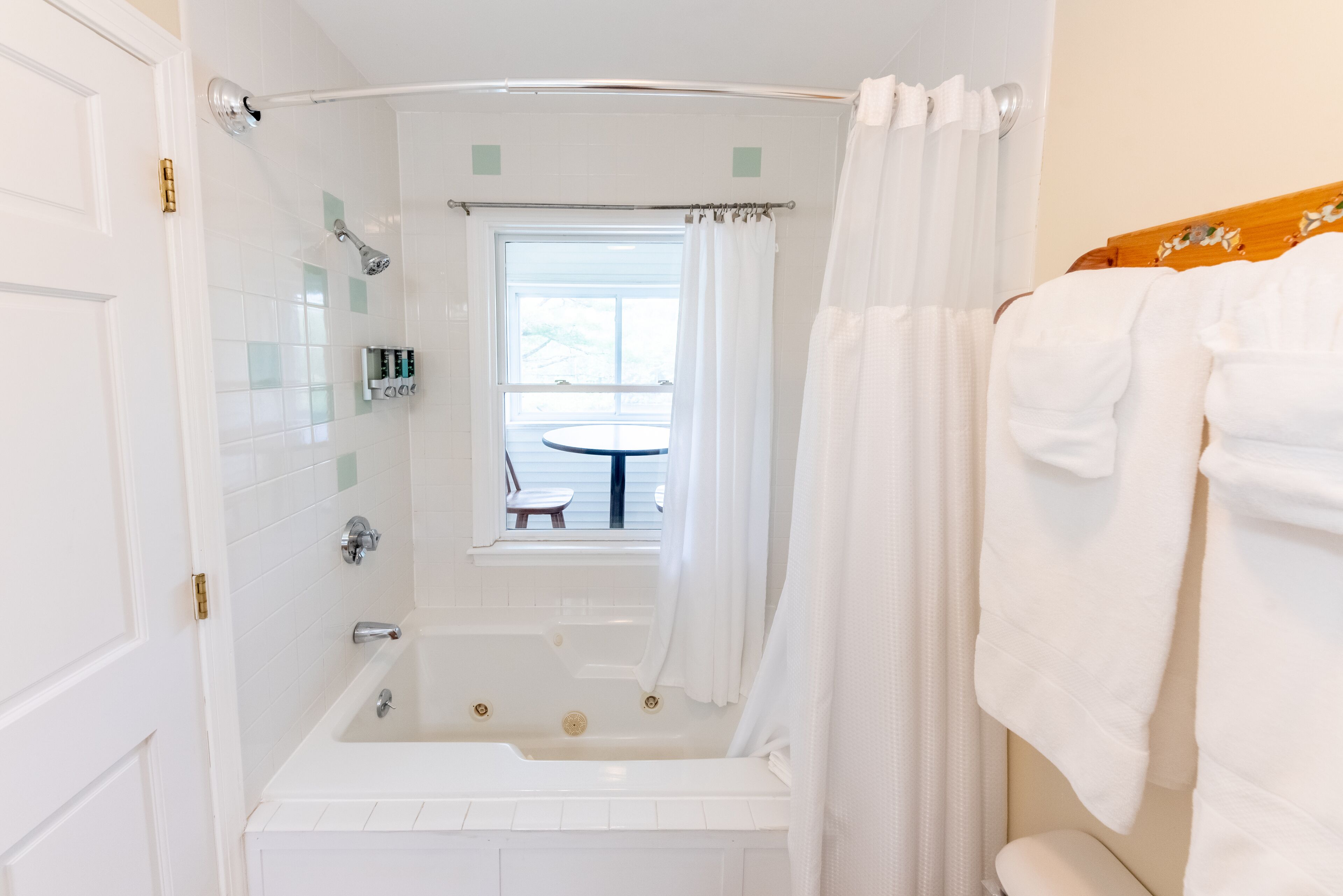 A bathroom with a bathtub, a shower, and a window.