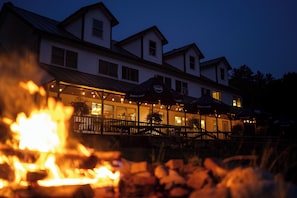 A building with a covered outdoor seating area and a fire in the foreground.