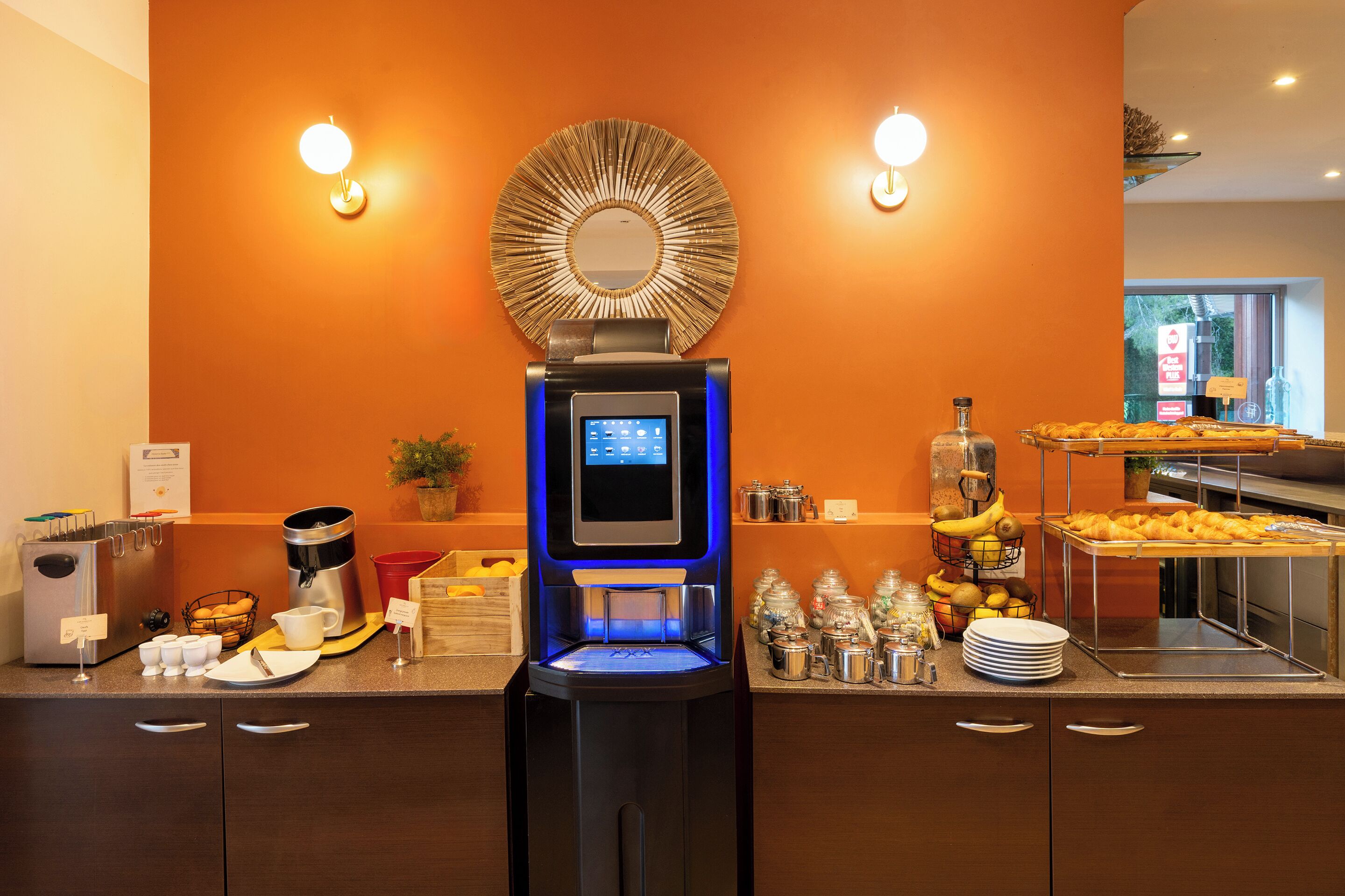 Ein Selbstbedienungs-Frühstücksbuffet mit Kaffeemaschine, Teeausgabe und einer Auswahl an Speisen.