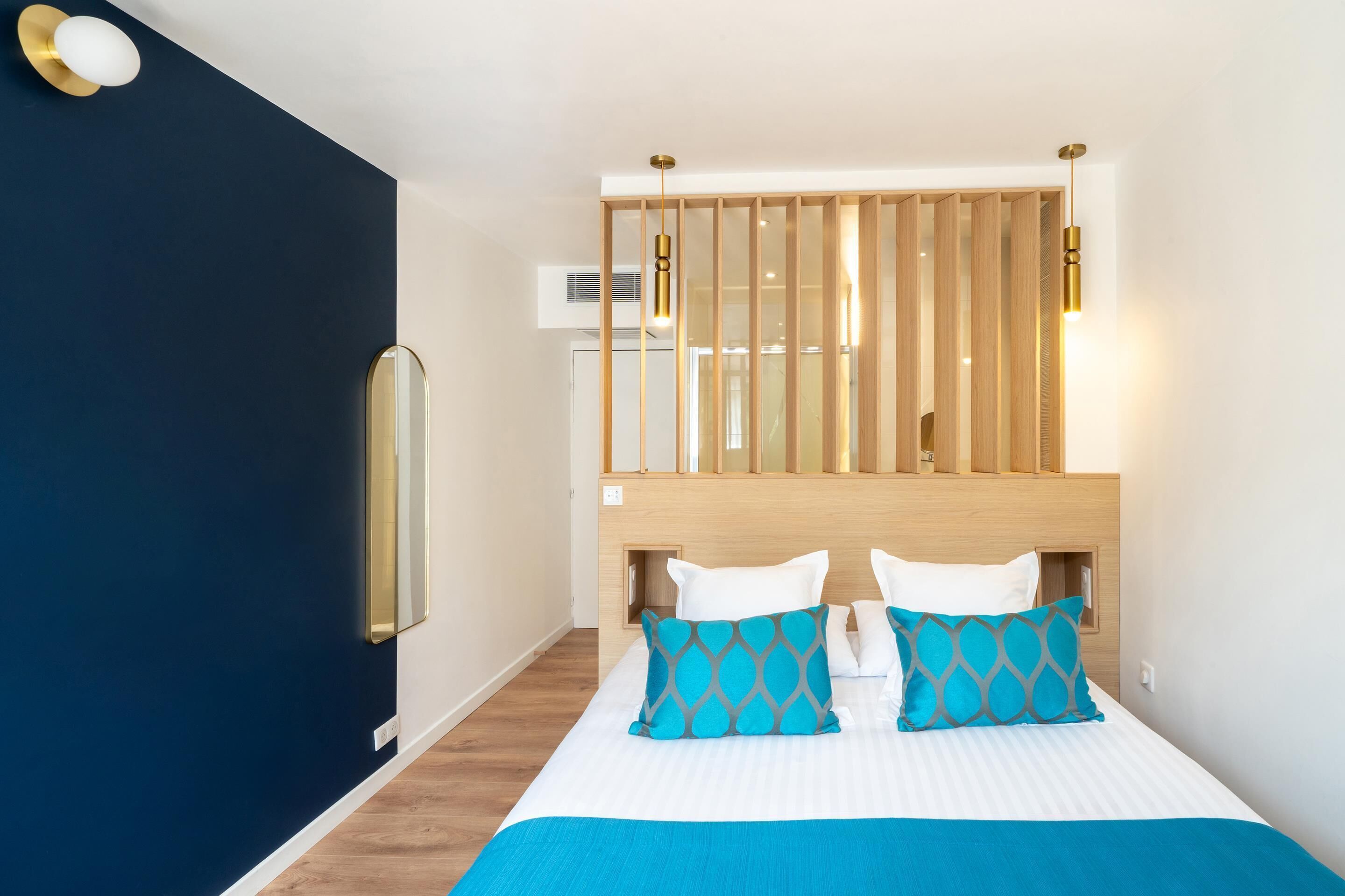 Een hotelkamer met een bed, een houten hoofdeinde en een nachtkastje.