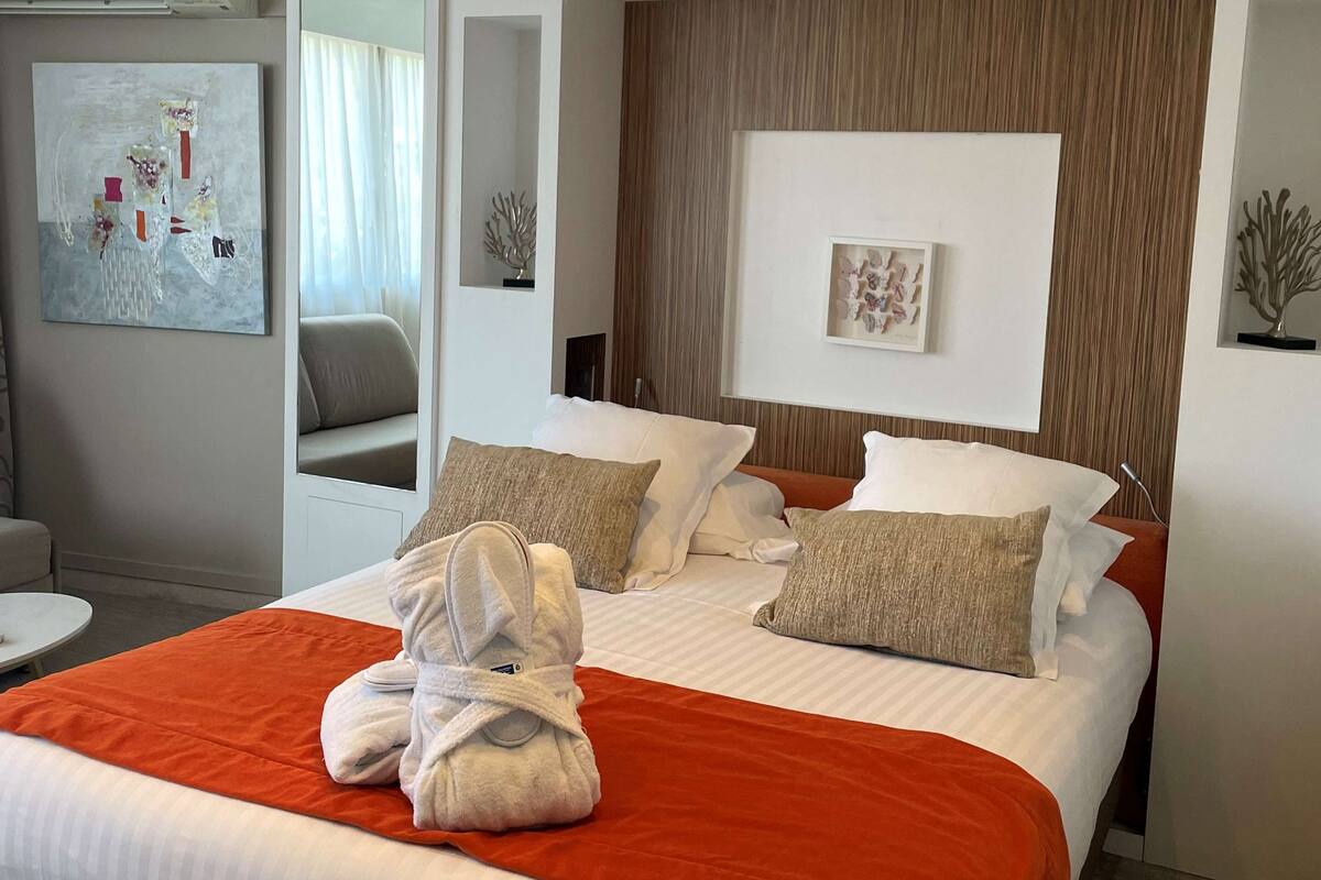 A modern hotel room with a large bed, a seating area, and artwork on the walls.