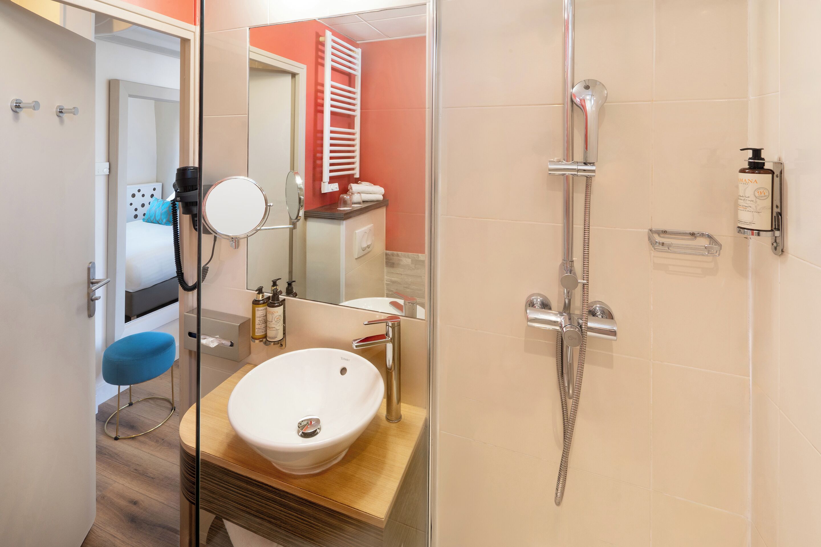 A modern bathroom with a white sink, a handheld showerhead, and a towel rack.