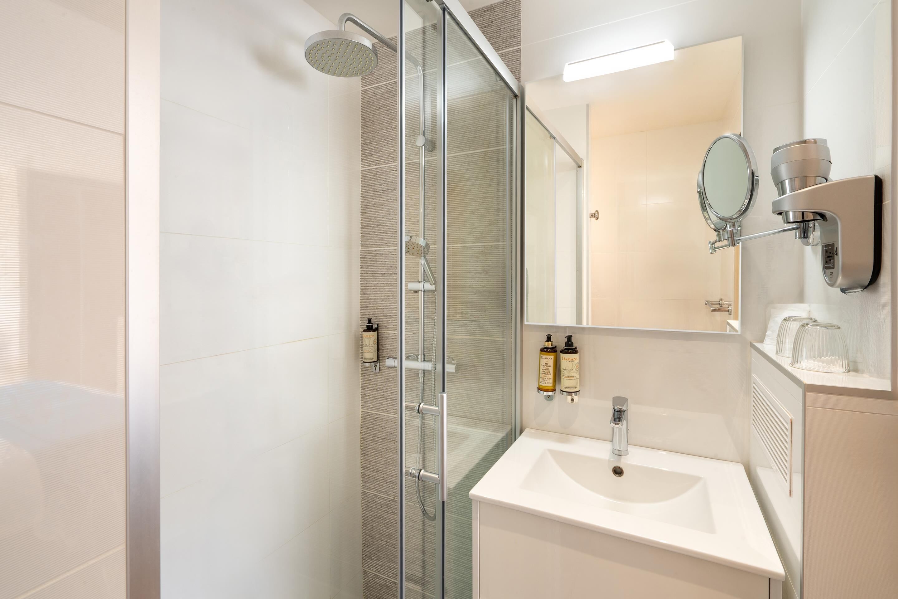 A modern bathroom with a glass shower enclosure, a white sink, and a large mirror.