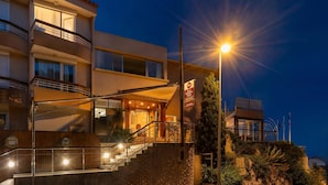 Un hotel de varios pisos con balcón, una escalera y una entrada bien iluminada.