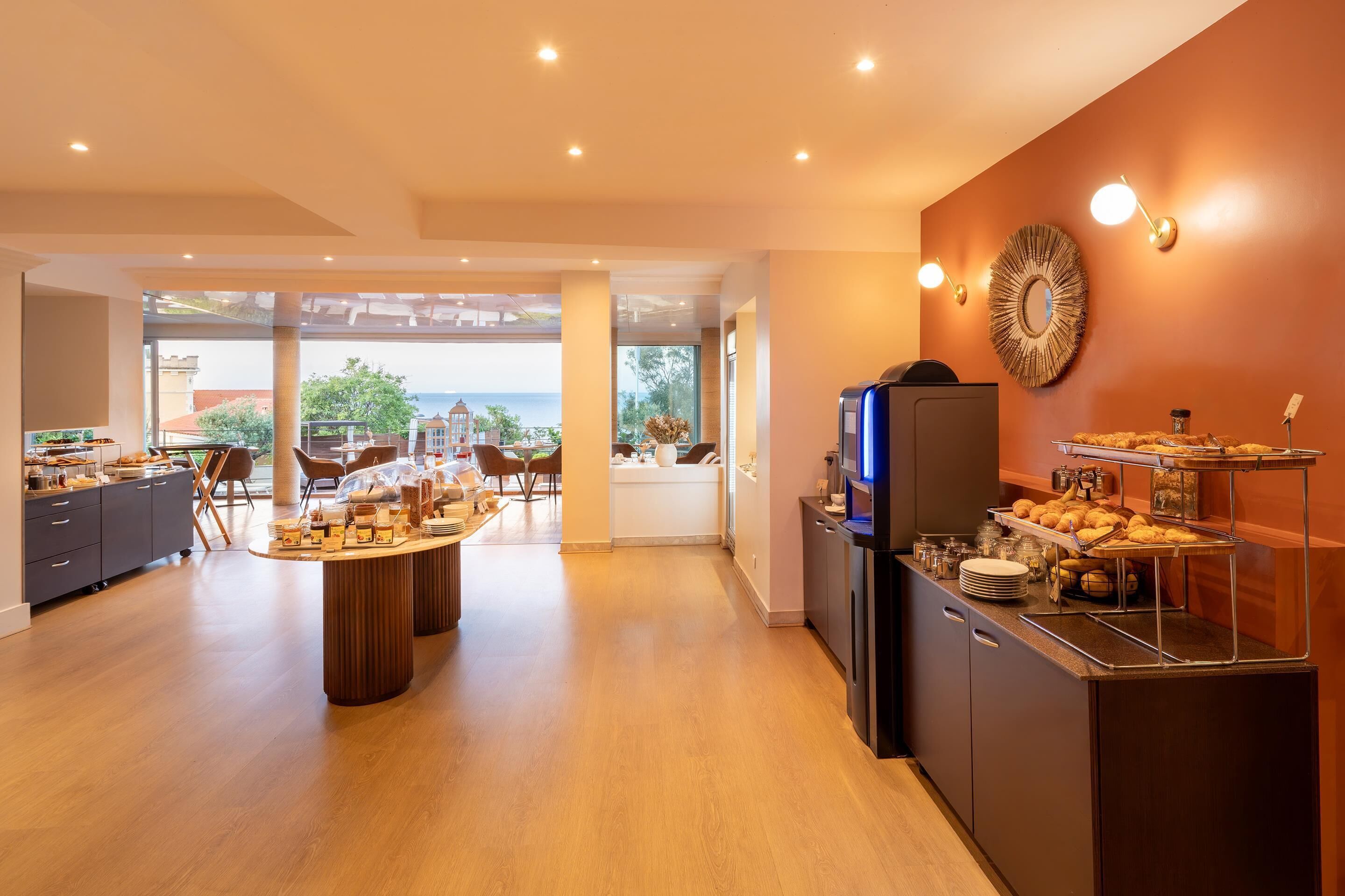A modern kitchen with a buffet setup, large windows, and a view of the sea.