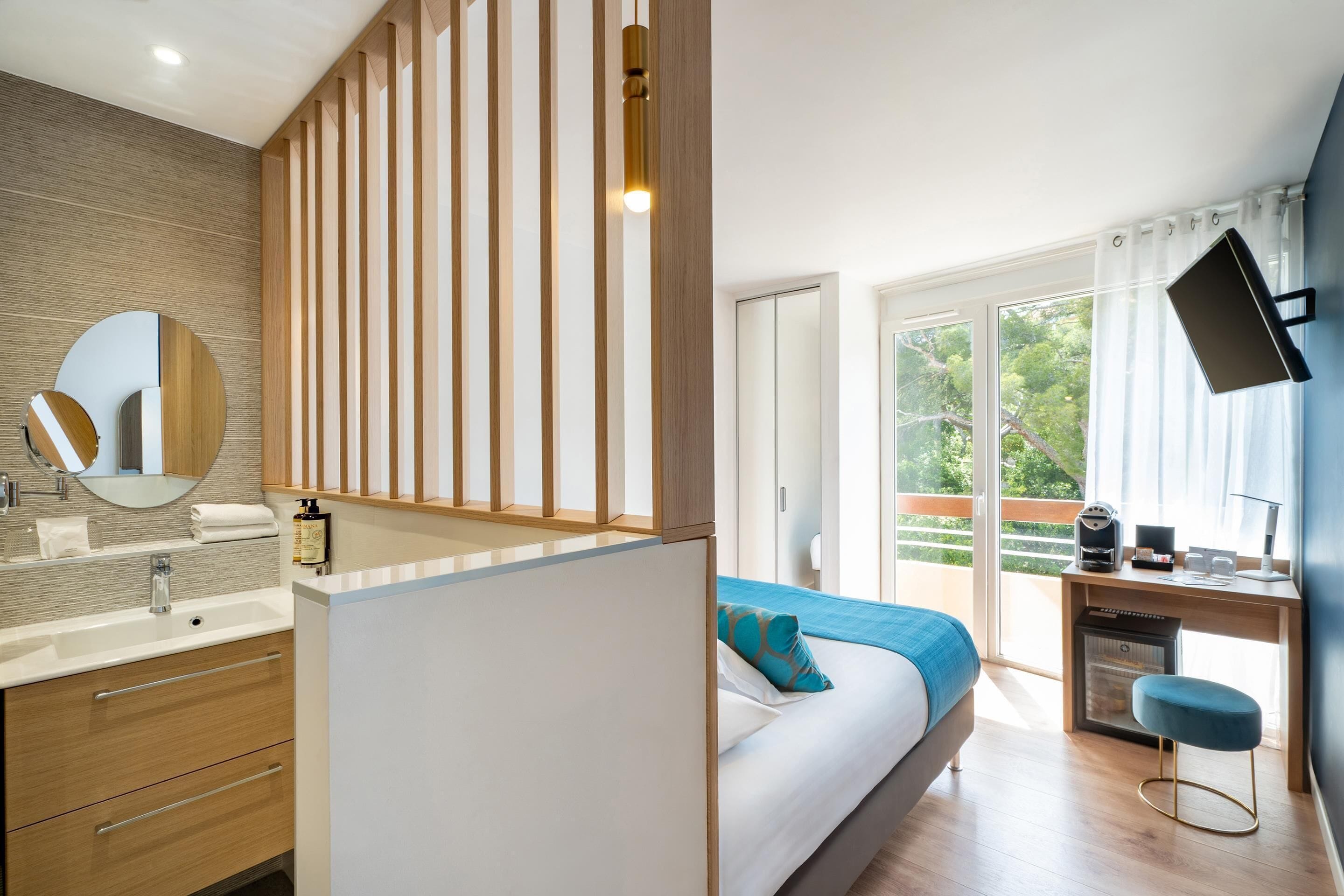 A modern bedroom with a large bed, a desk, and a view of the outdoors.