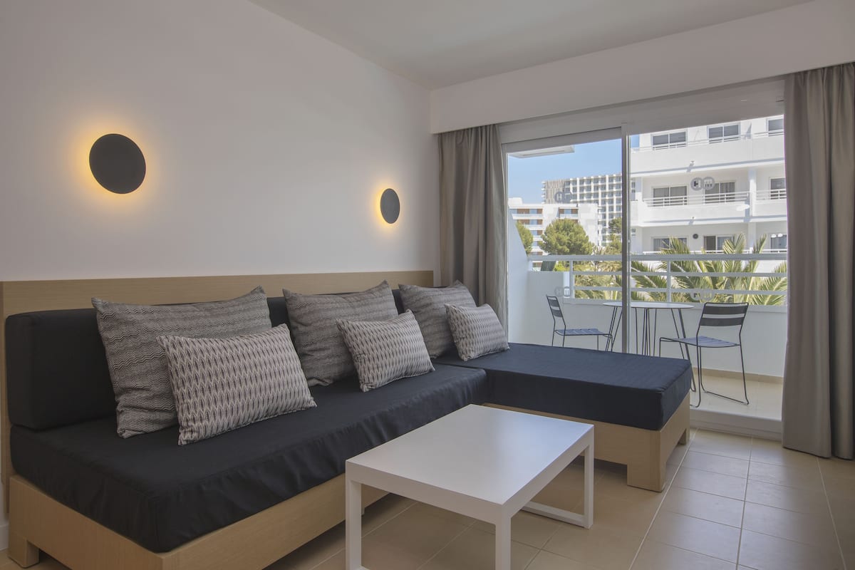 A modern living room with a sofa, a coffee table, and a balcony with outdoor furniture.