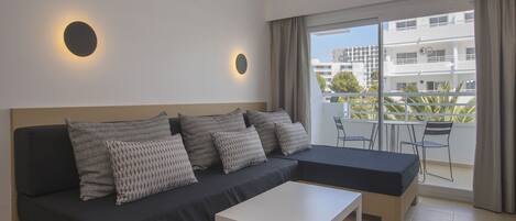 A modern living room with a sofa, a coffee table, and a balcony with outdoor furniture.