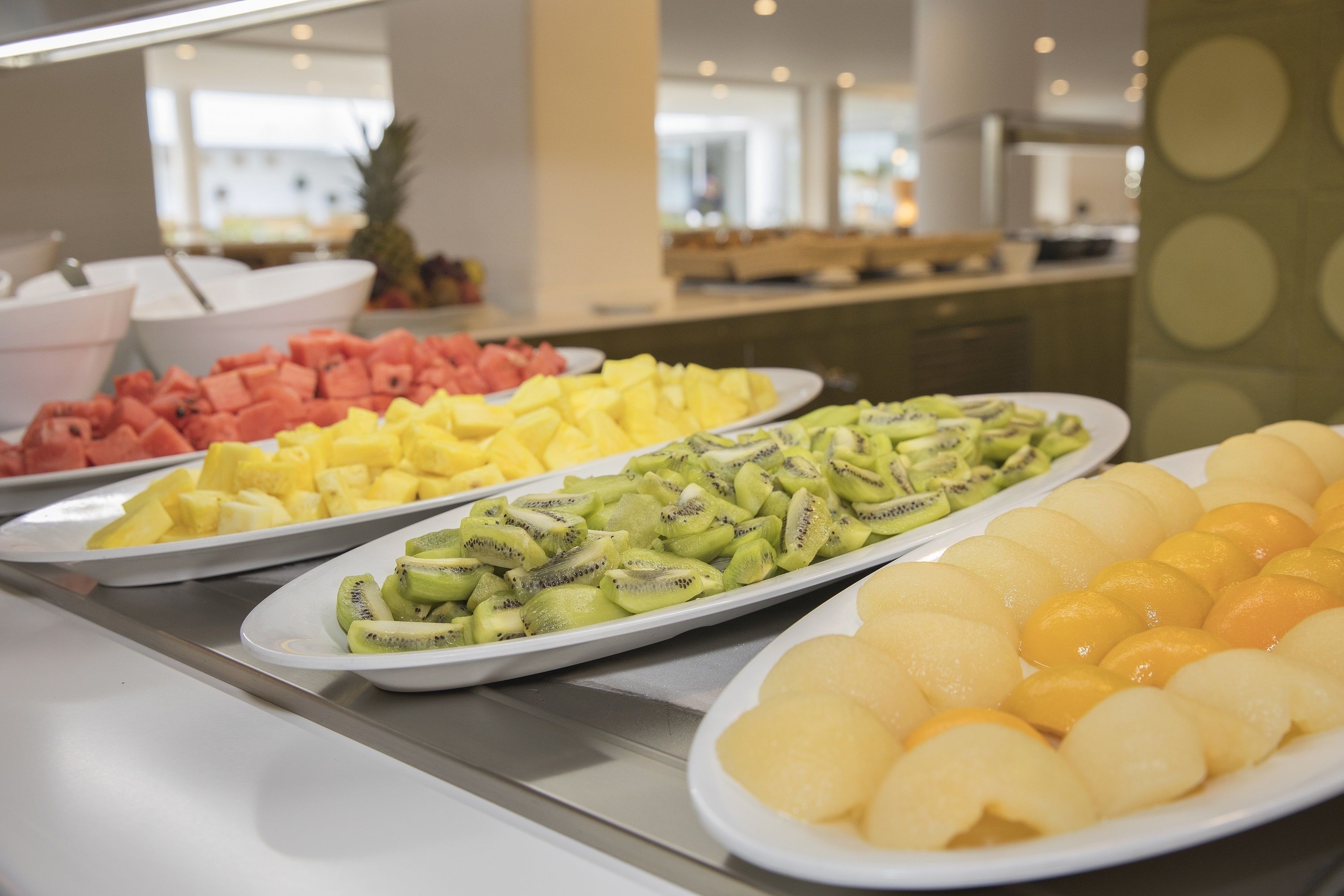 A buffet with various fruits including watermelon, pineapple, kiwi, and yellow fruit.