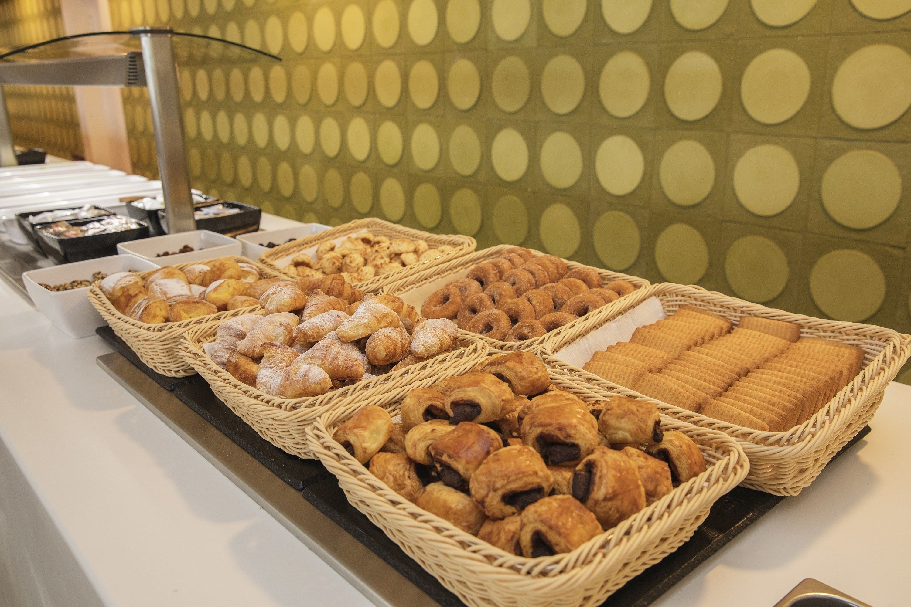Un bufé con diversas opciones de panadería expuestas en cestas de mimbre.
