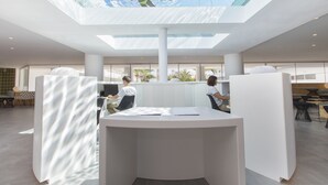 A modern office space with a central island desk, glass ceiling, and natural light. - HM Martinique Aparthotel (Calvia)